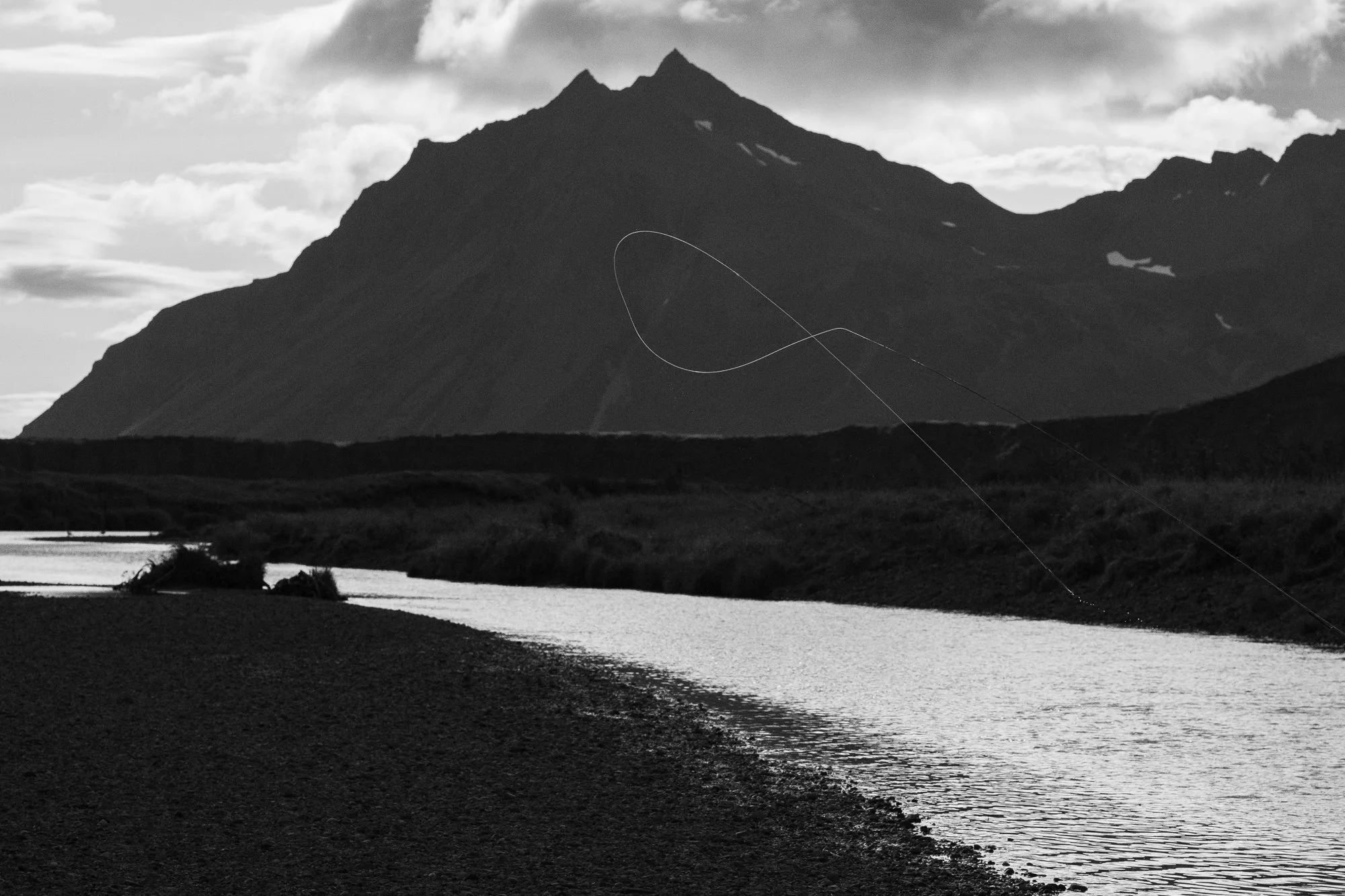 Fly fishing river winding through an Alaskan landscape beneath a mountain