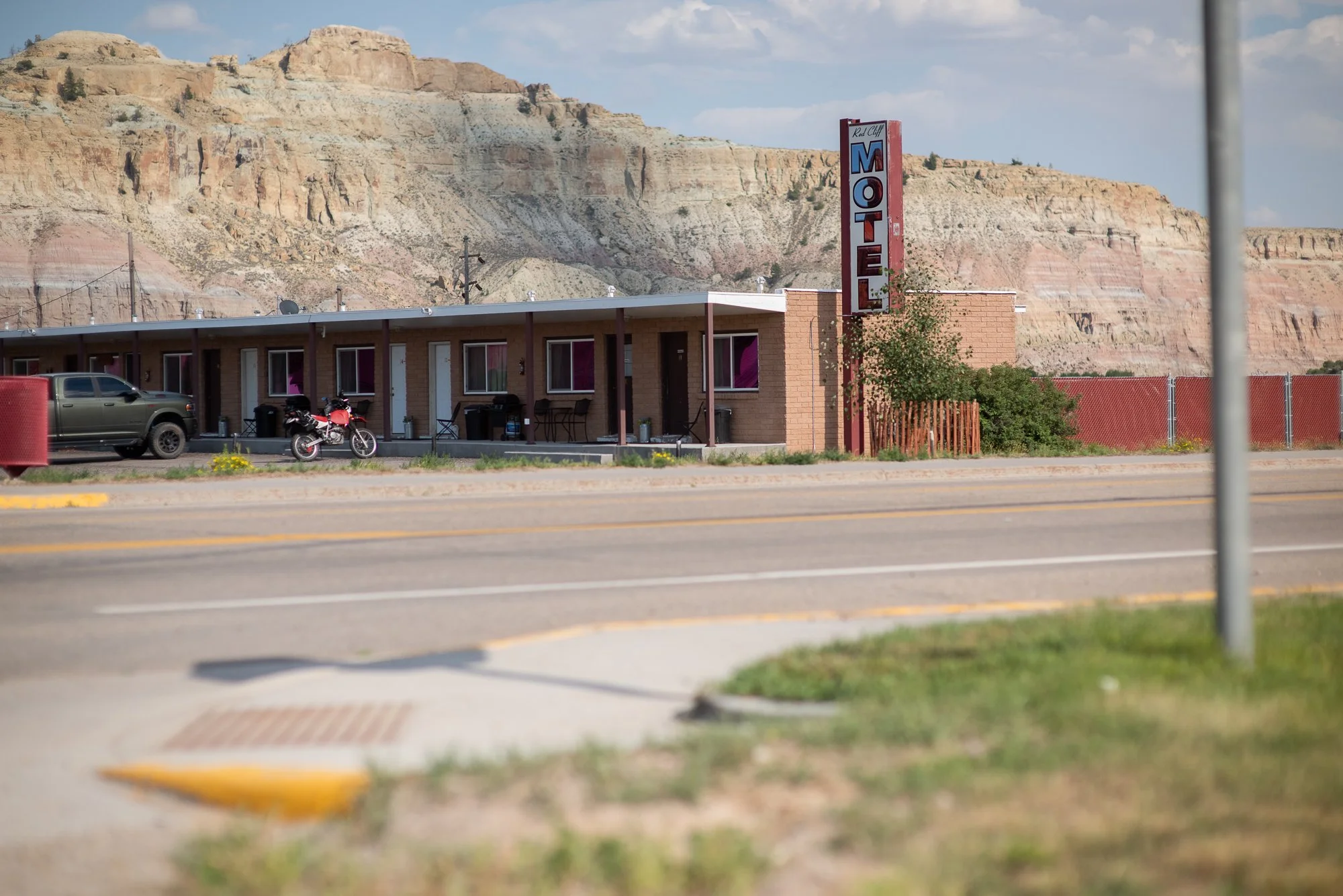 Old motel beside a Wyoming road with rocky cliffs behind it