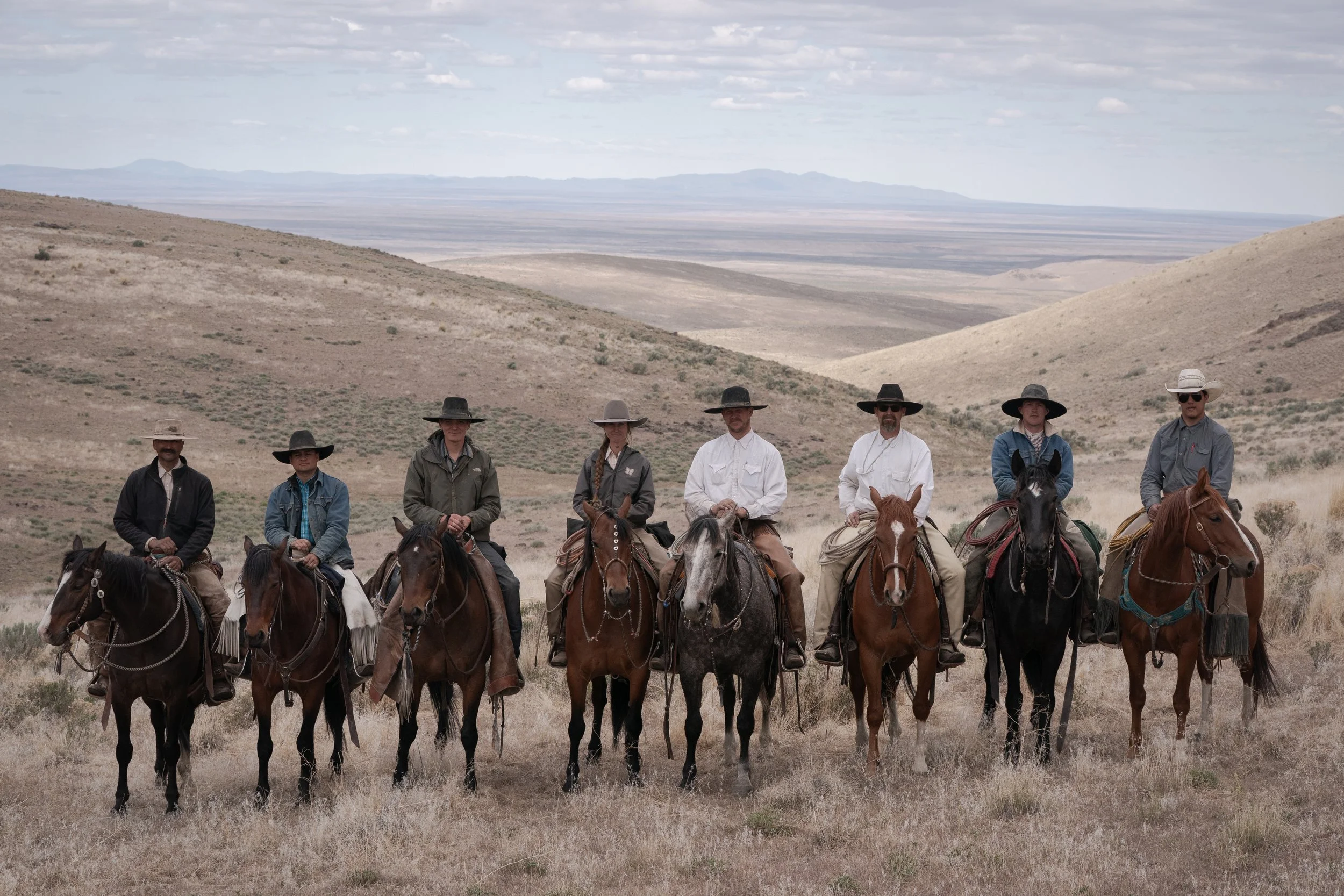 Group of cowboys on horseback photographed in open ranch country in the American West