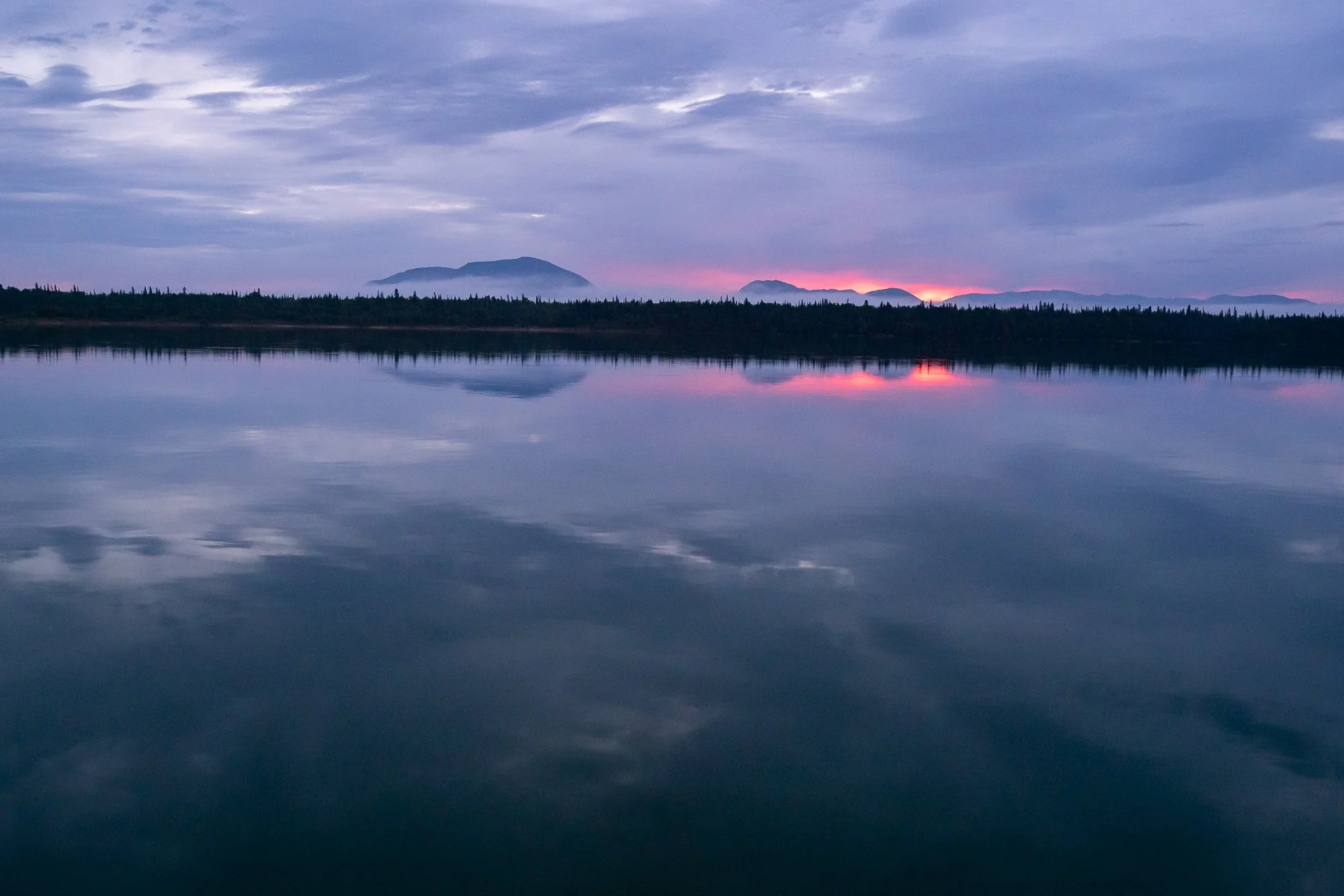 Alaskan lake reflecting a sunset with mountains in the distance