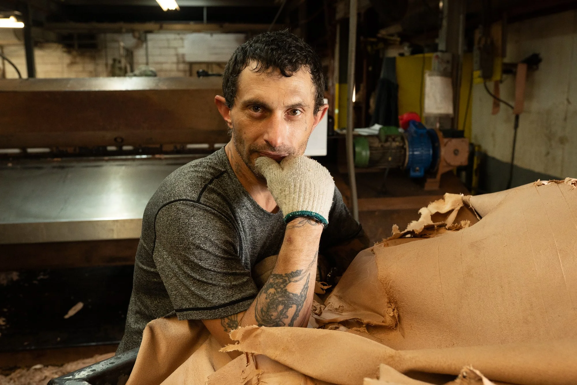 A Wickett & Craig worker stands beside a large brown leather hide inside the Pennsylvania tannery