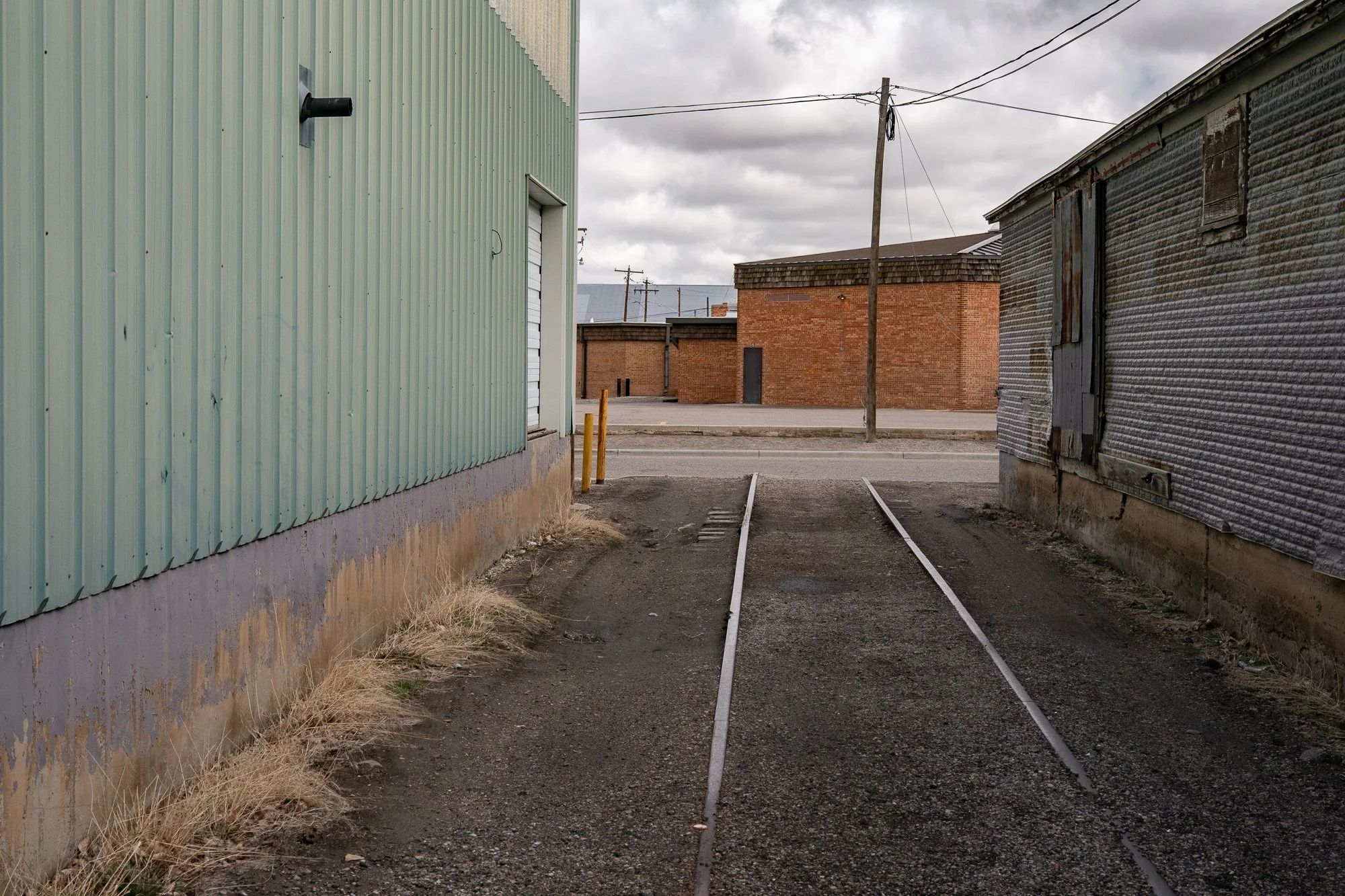 Railroad tracks running through an industrial alley between metal buildings in Rock Springs Wyoming