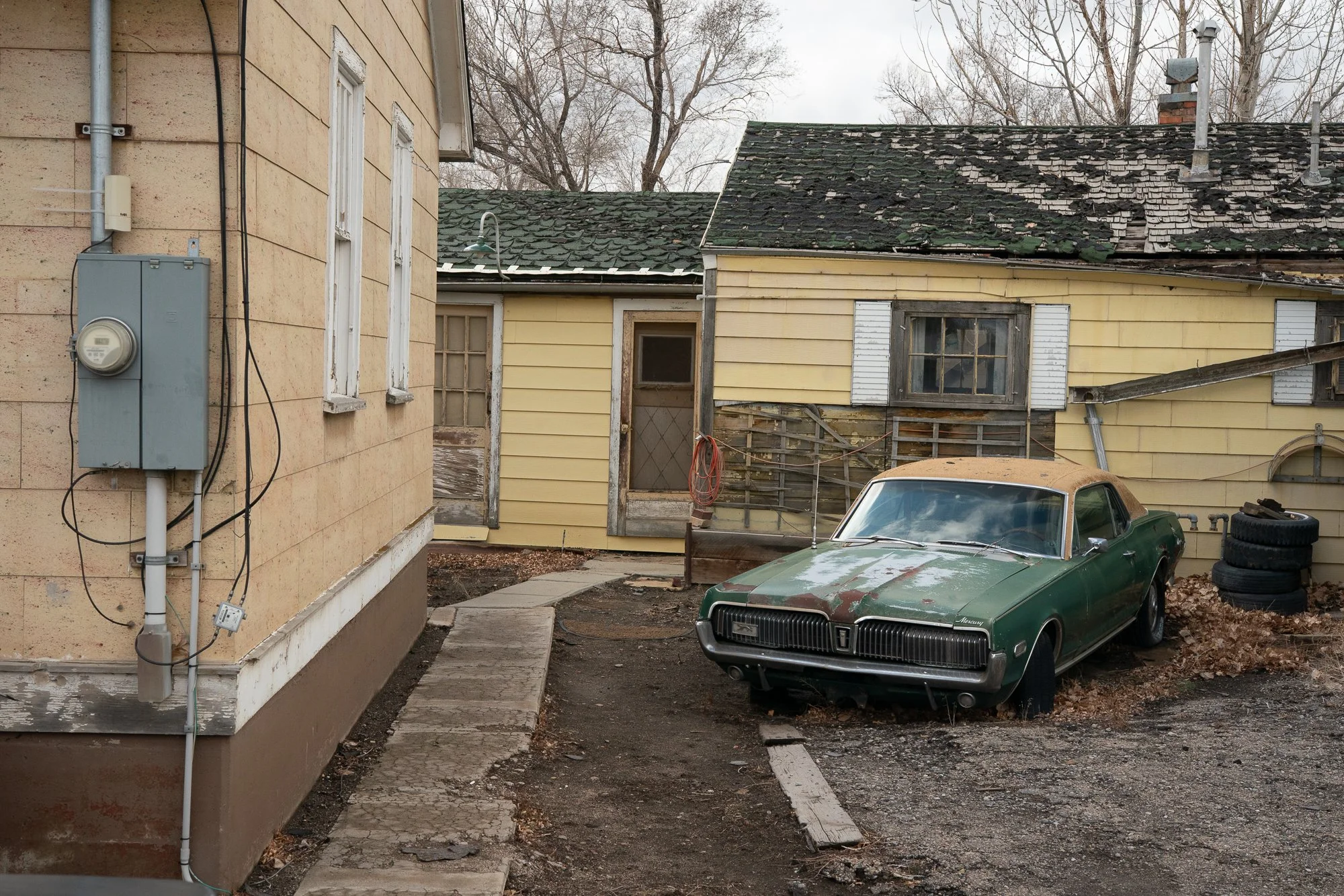 Weathered green vintage car parked beside an old Wyoming building