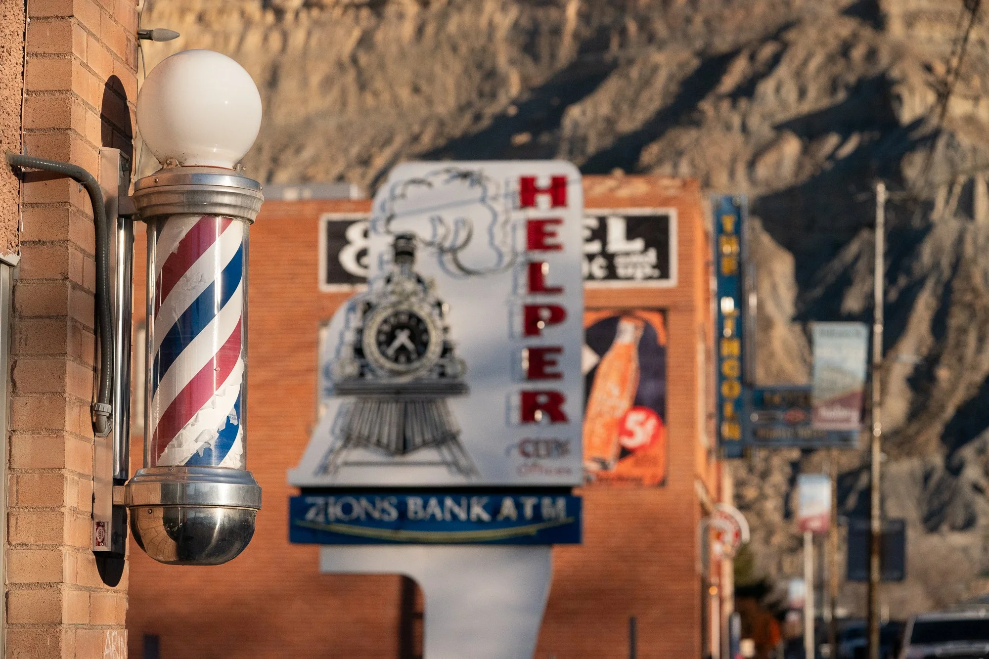 Classic barber pole on Main Street in Helper Utah with vintage signs