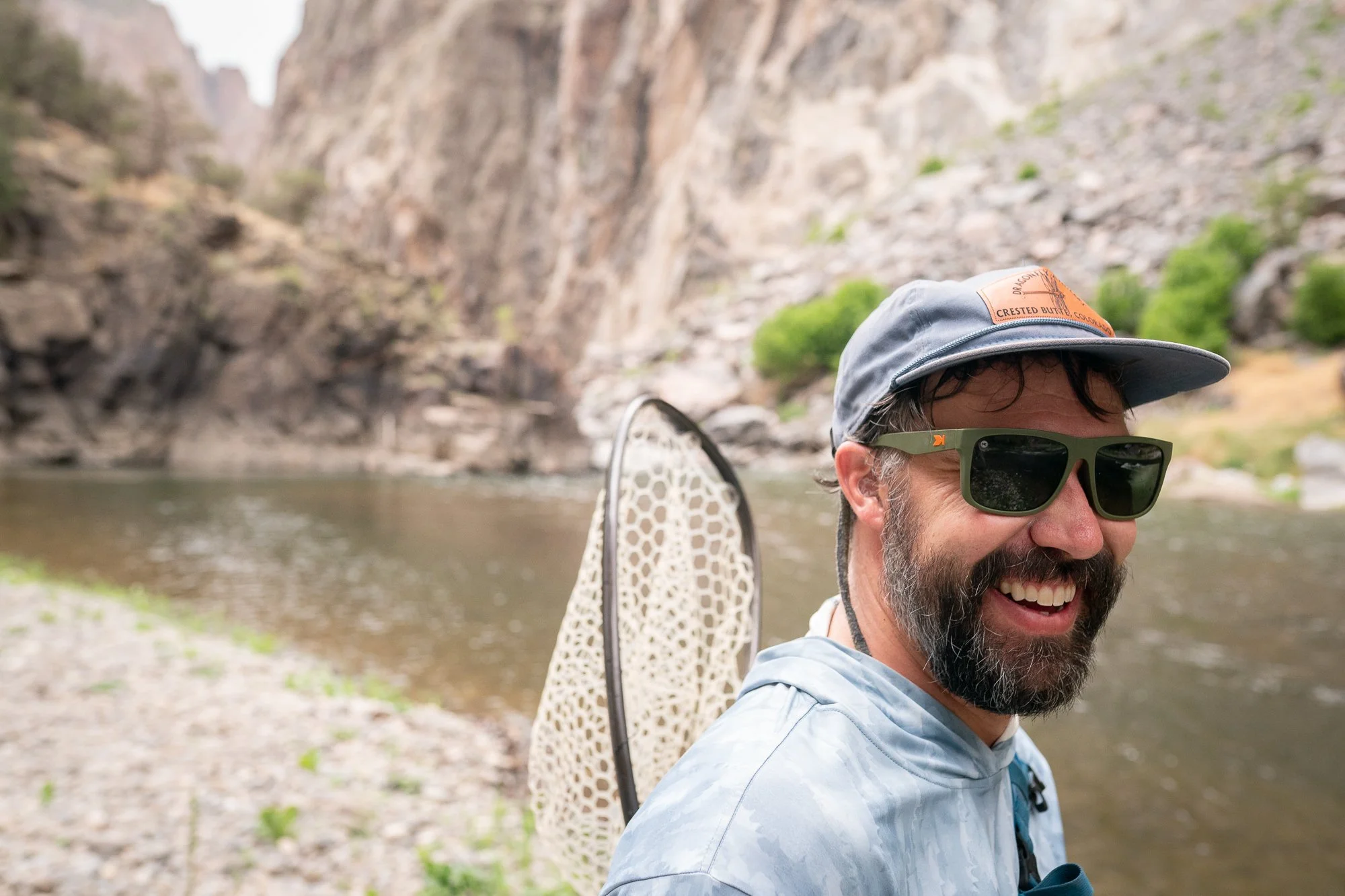 A smiling angler stands beside the Gunnison River after time spent in the Black Canyon