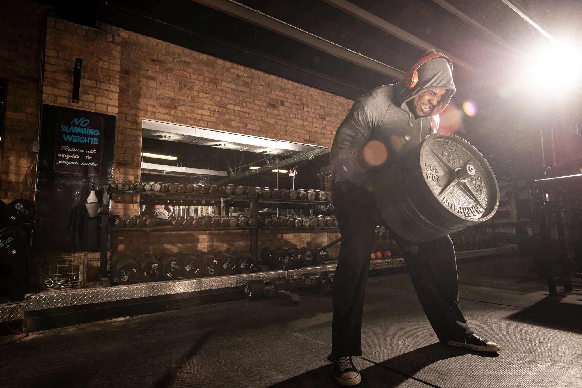 athlete lifting heavy weight plate in gritty gym with dramatic lighting