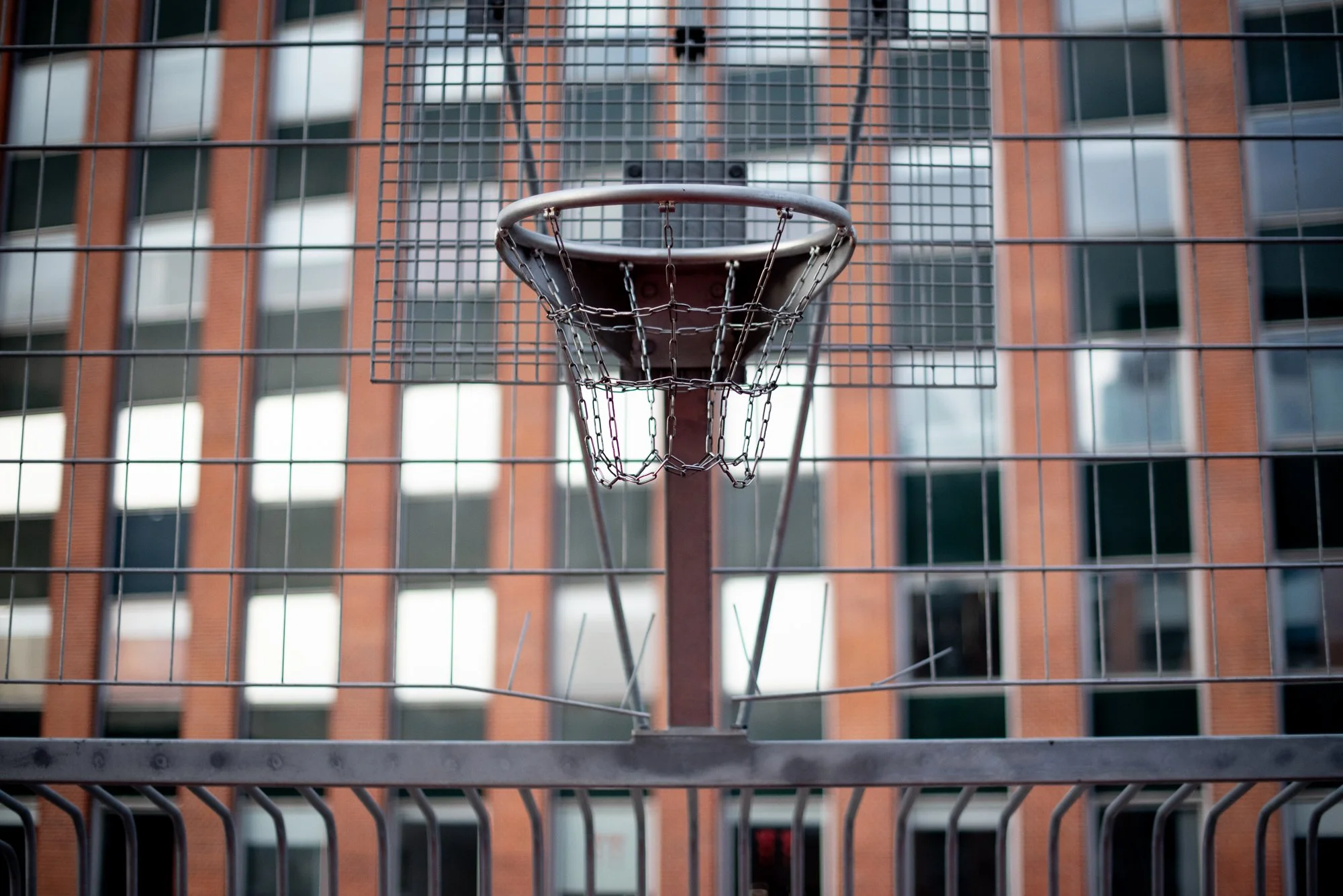 Outdoor basketball hoop with a chain net set against an urban building facade in Europe.