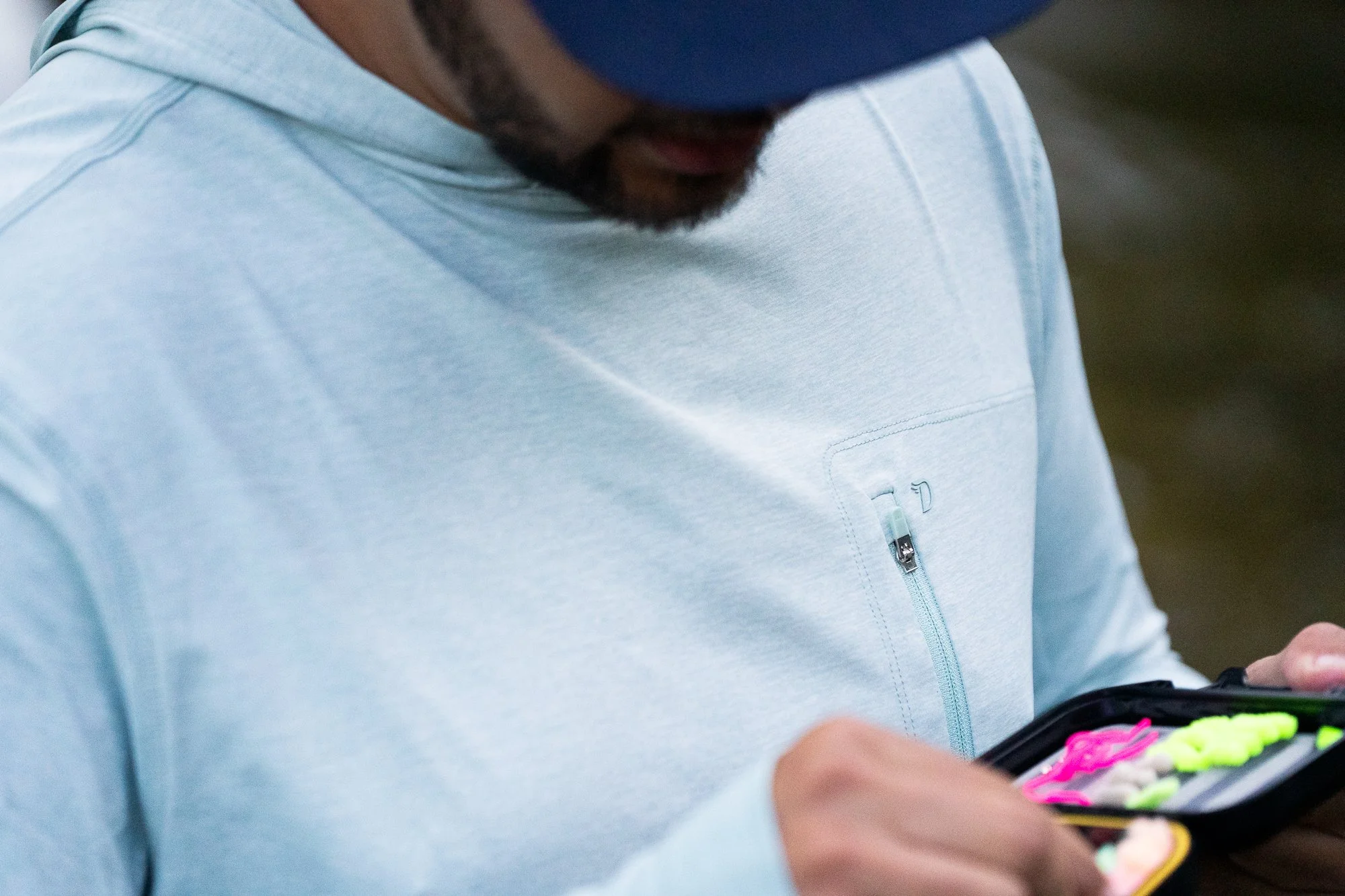 Close-up of a Duck Camp shirt as an angler looks through a fly box near the river