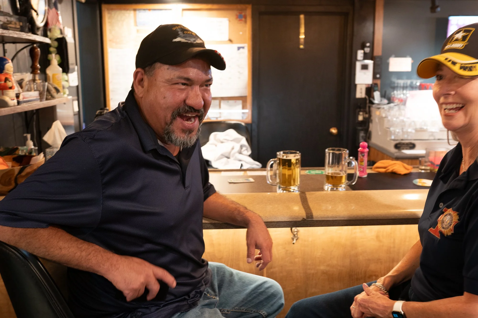 Veterans laughing while seated at a bar inside a VFW hall during a brand campaign