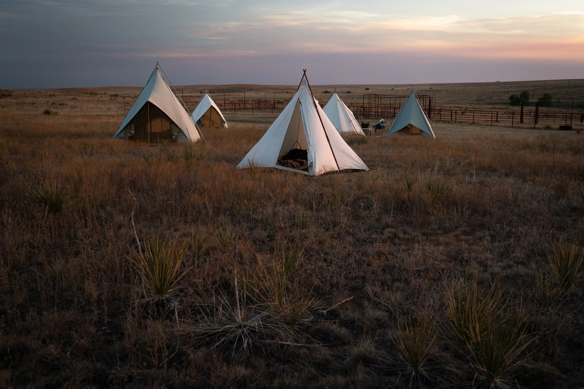 Canvas cowboy camp tents set up on the prairie at sunset at the 6666 Ranch in Texas.  On-Page Caption: