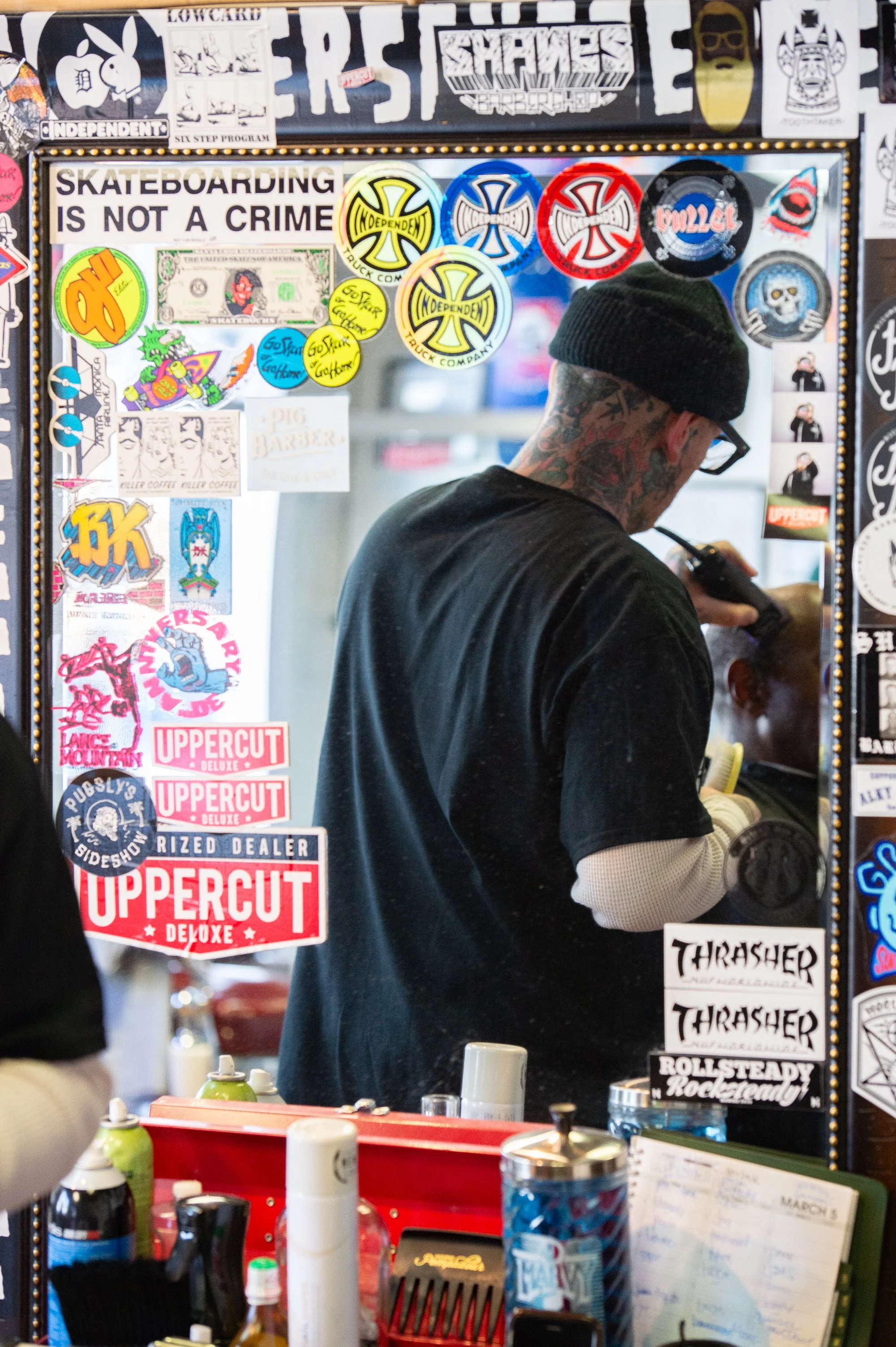 barber working through mirror covered in stickers inside Shane's Barbershop San Mateo