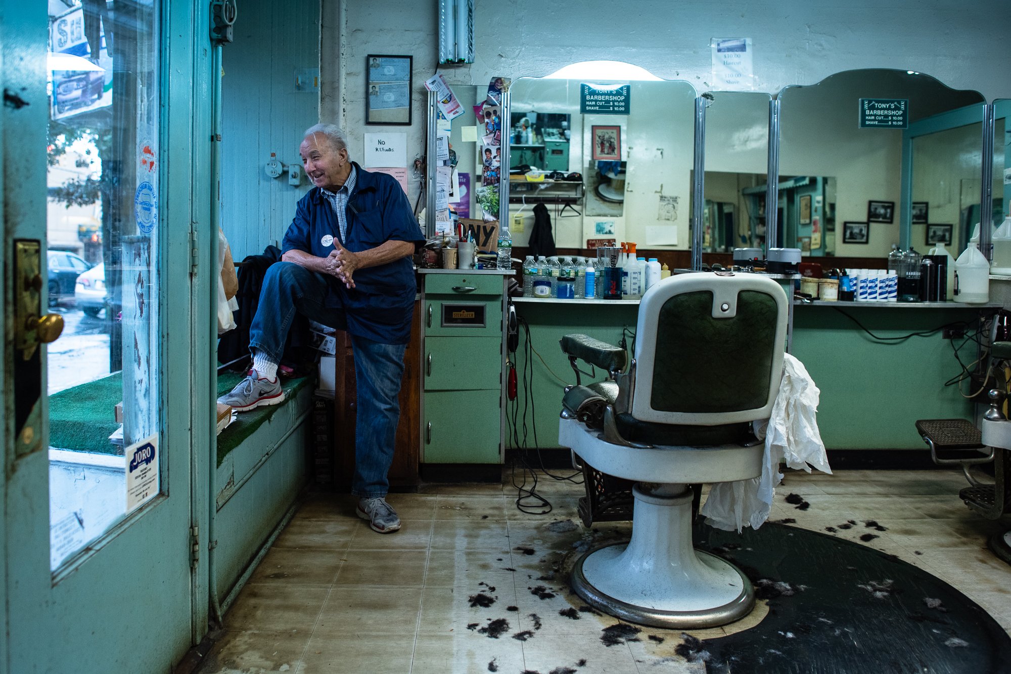 An elderly barber pauses between appointments inside Tony’s Barbershop in Brooklyn, New York.