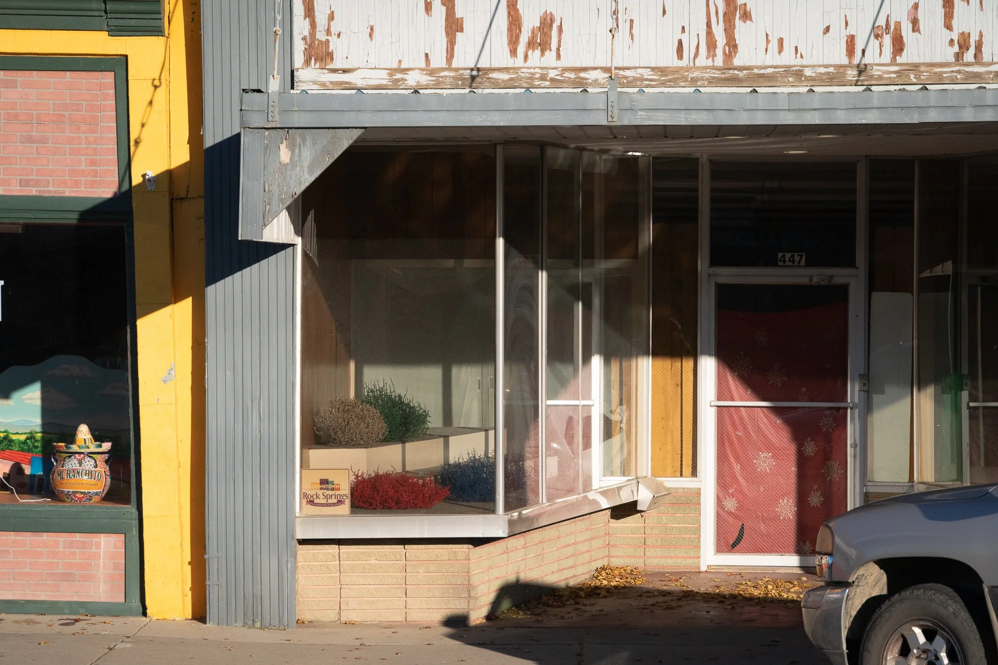 Storefront in Rock Springs with peeling paint, a colorful ceramic jar in the window, and the number 447 by the entrance.