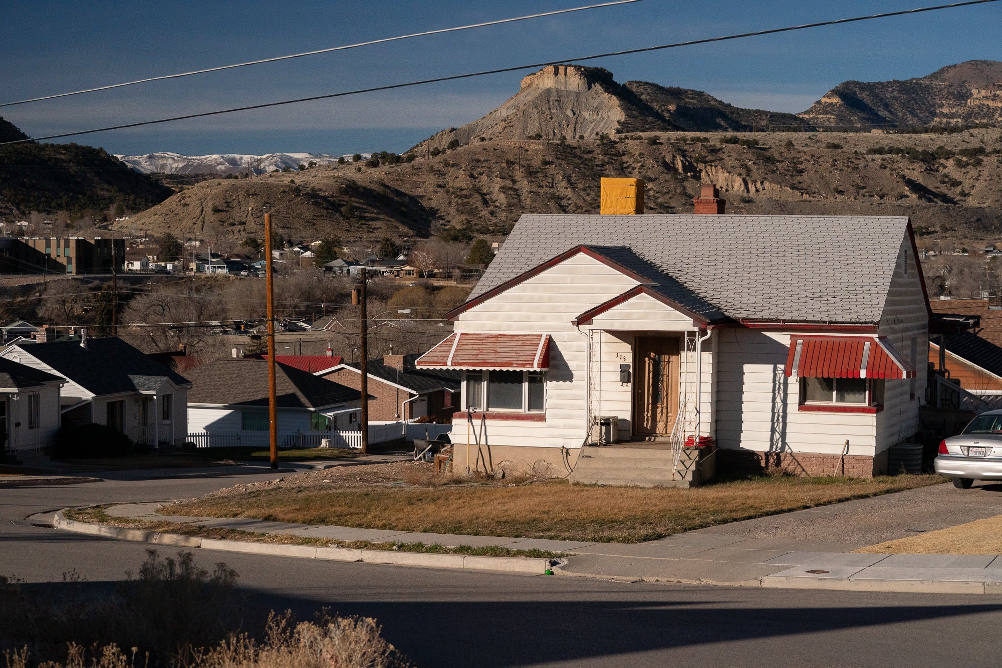 Small hillside home in Helper Utah with Book Cliffs and neighborhood behind