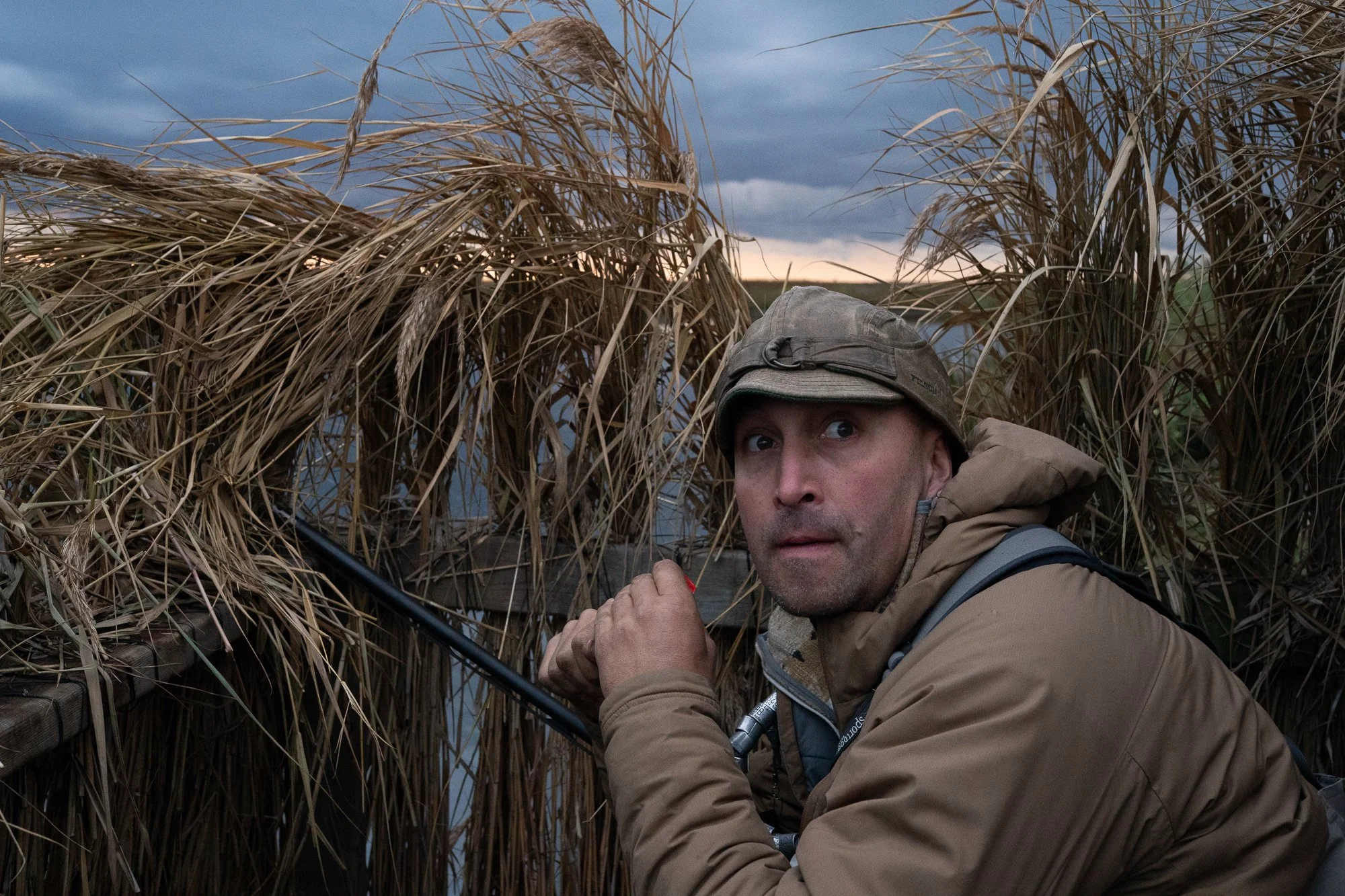 A duck hunter waits inside a marsh blind under storm clouds during hunting season in Ontario