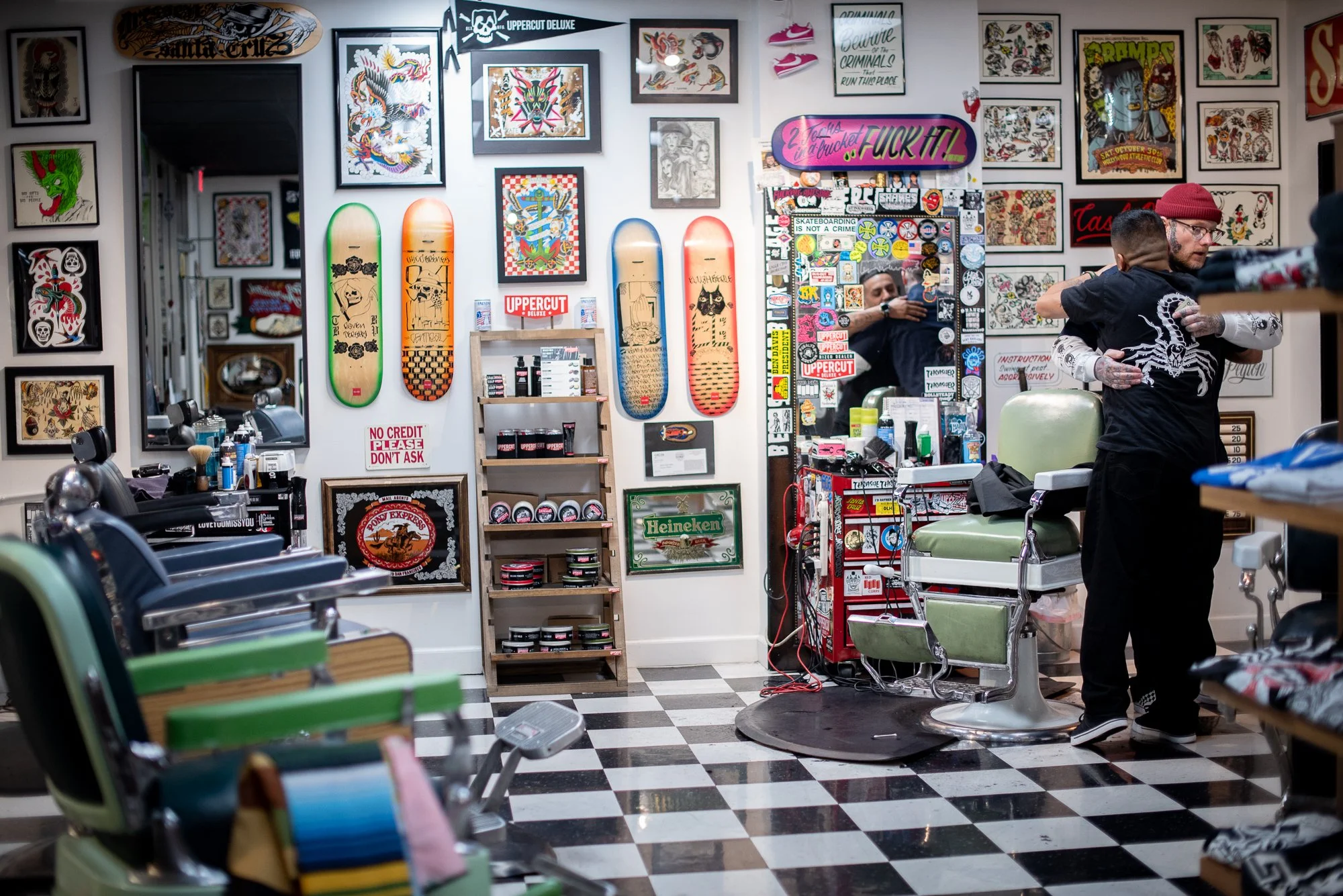 interior of Shane's Barbershop San Mateo with barber hugging client and tattoo artwork walls