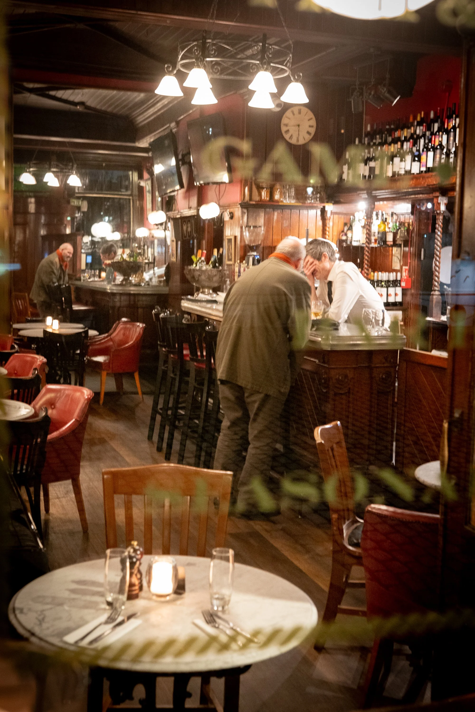 Man leaning on bar counter inside traditional Edinburgh pub at night