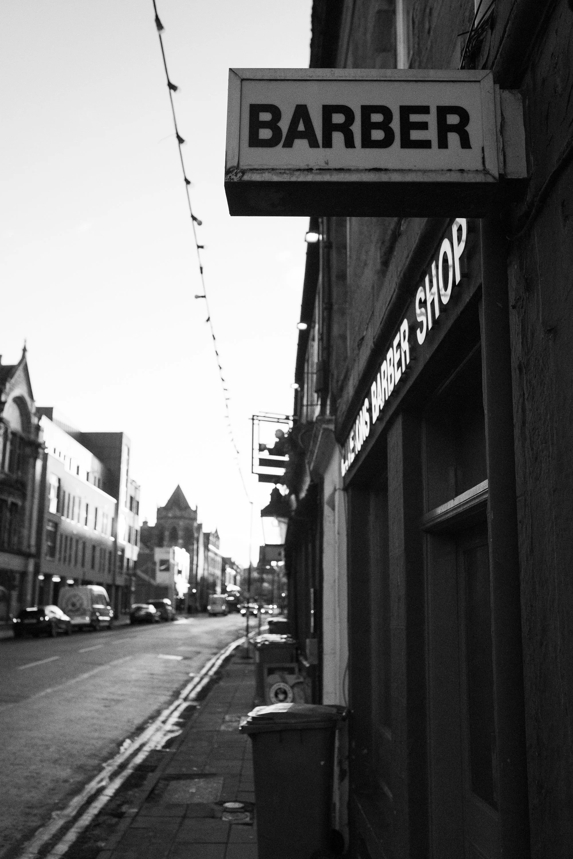 barber shop sign on empty street in scotland black and white photo