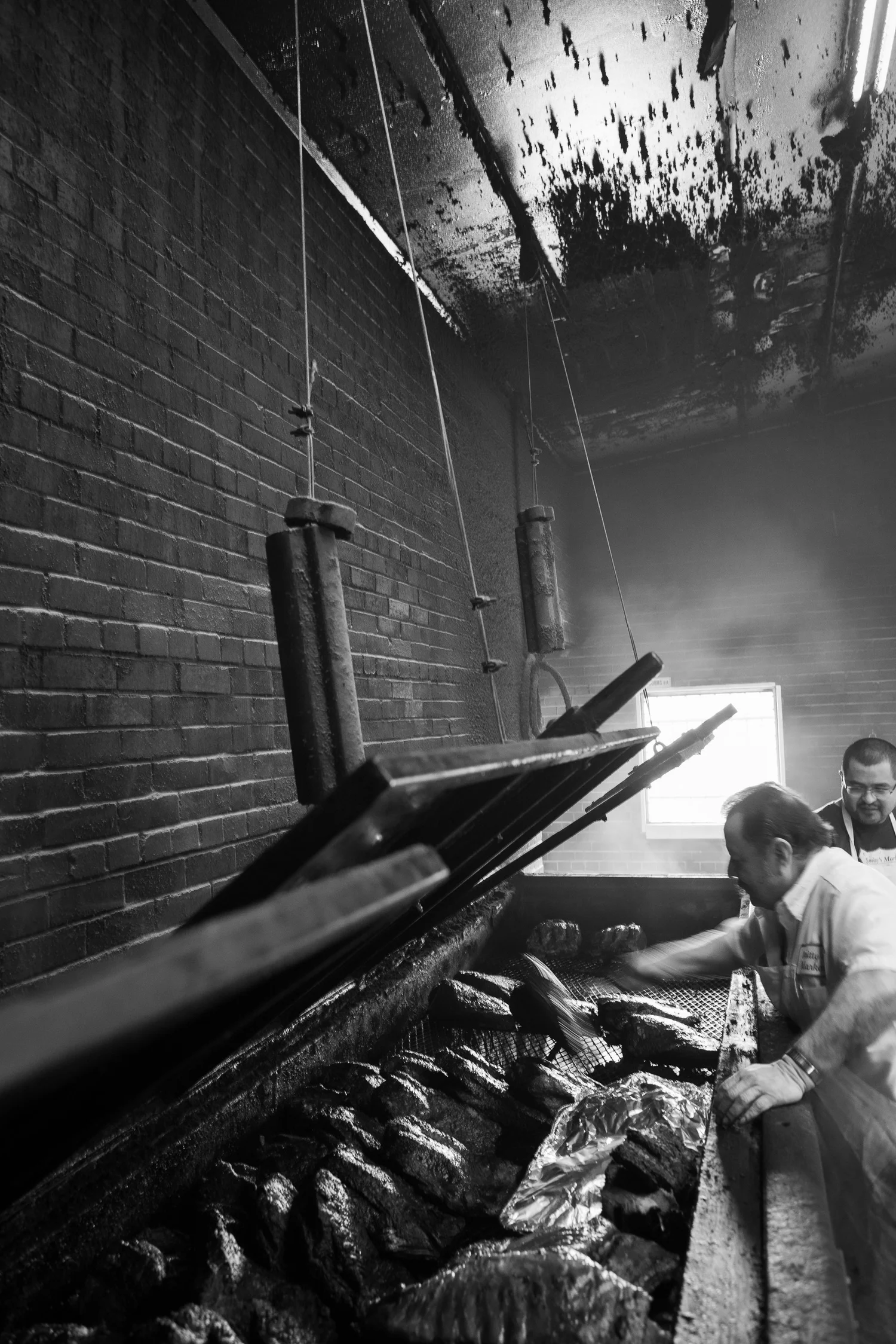 Smoke-blackened ceiling above pitmasters tending brisket at Smitty's Market in Lockhart
