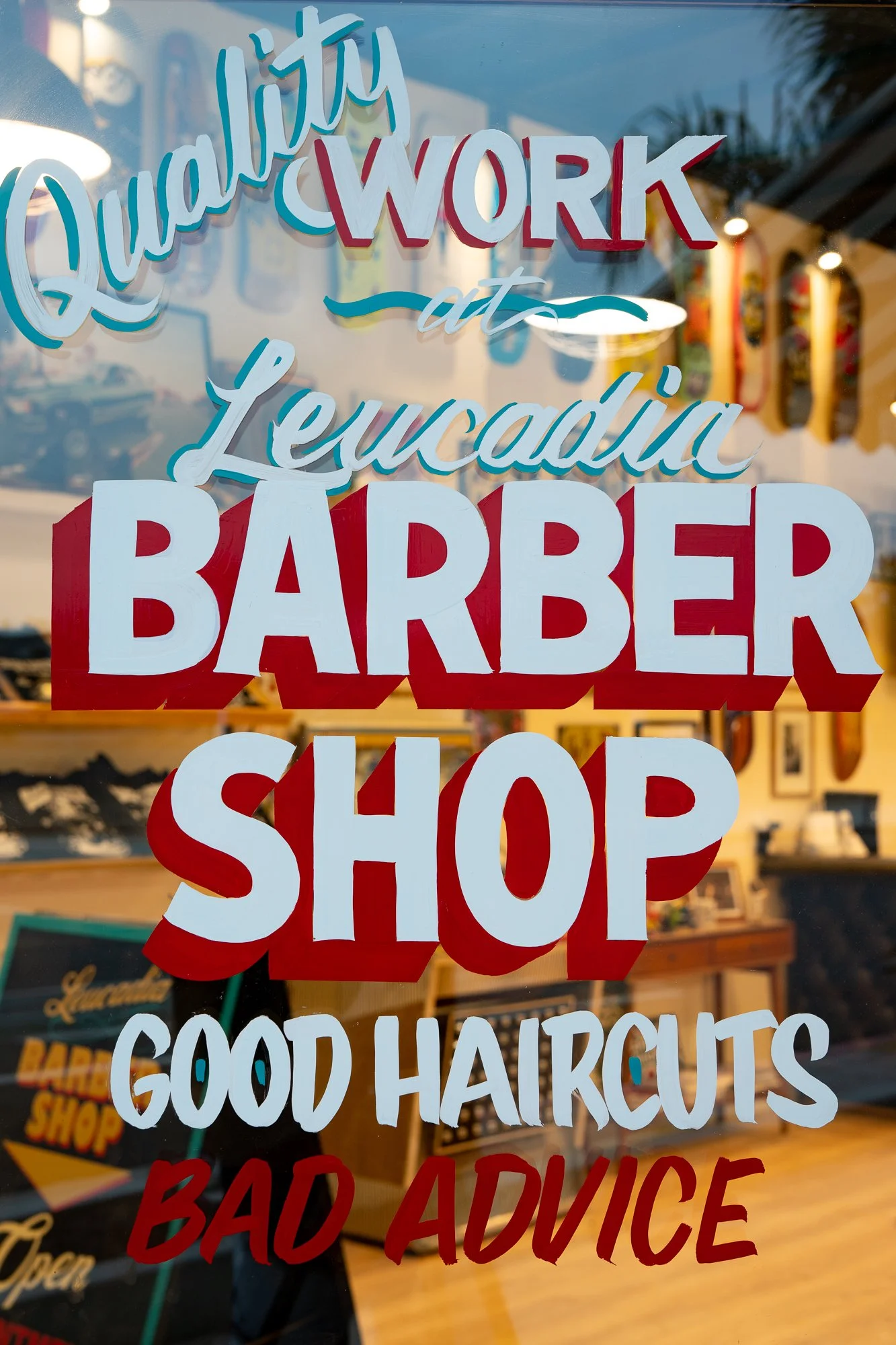 Window lettering reading “Quality Work at Leucadia Barber Shop” on the storefront in Encinitas, California.