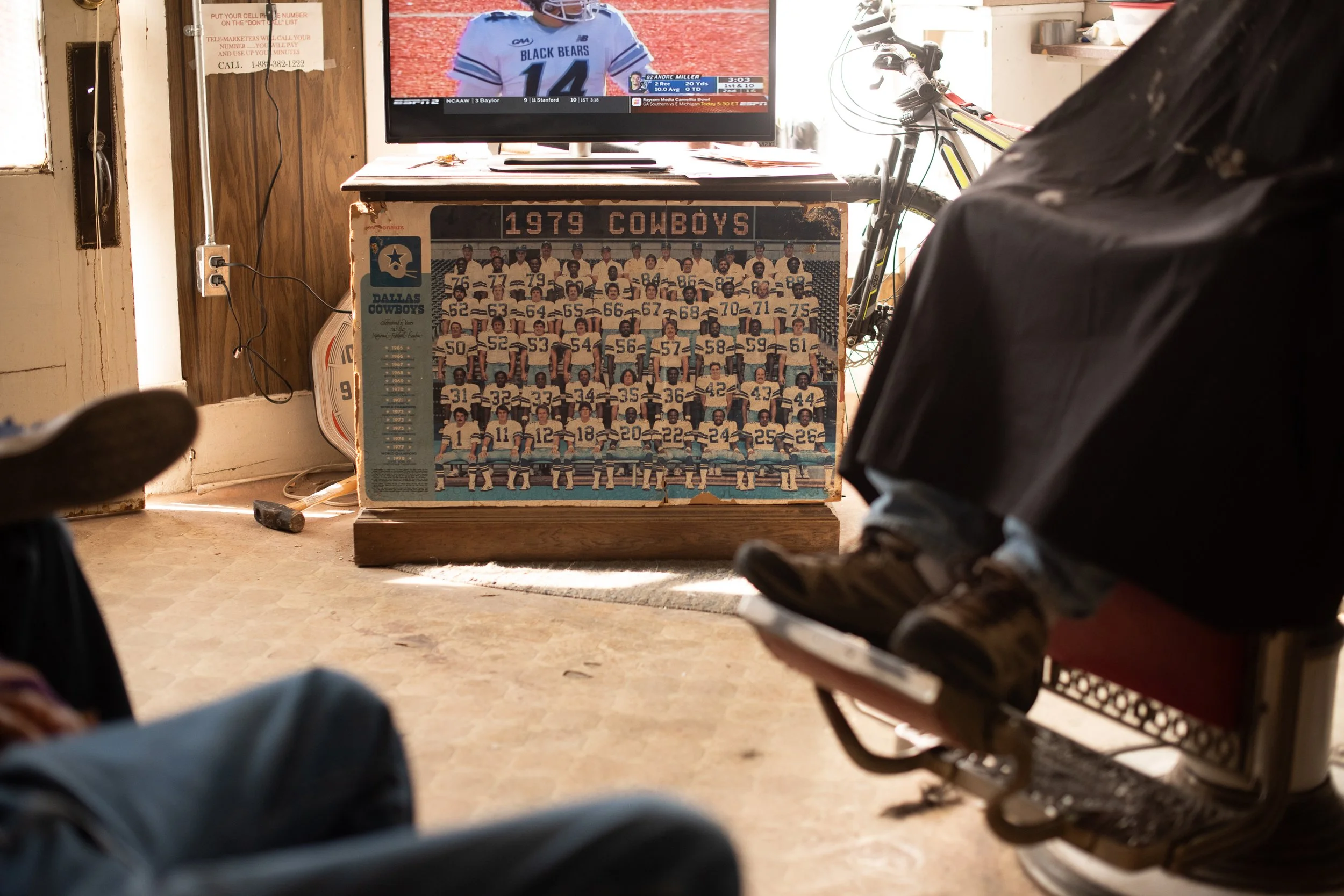 Worn 1979 Dallas Cowboys team poster displayed beneath a television inside a Marfa, Texas barbershop.