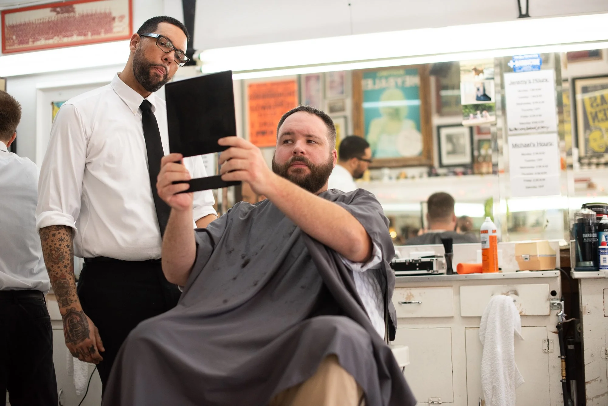 A barber holds up a mirror as a customer looks at his haircut inside Avenue Barbershop in Austin, Texas