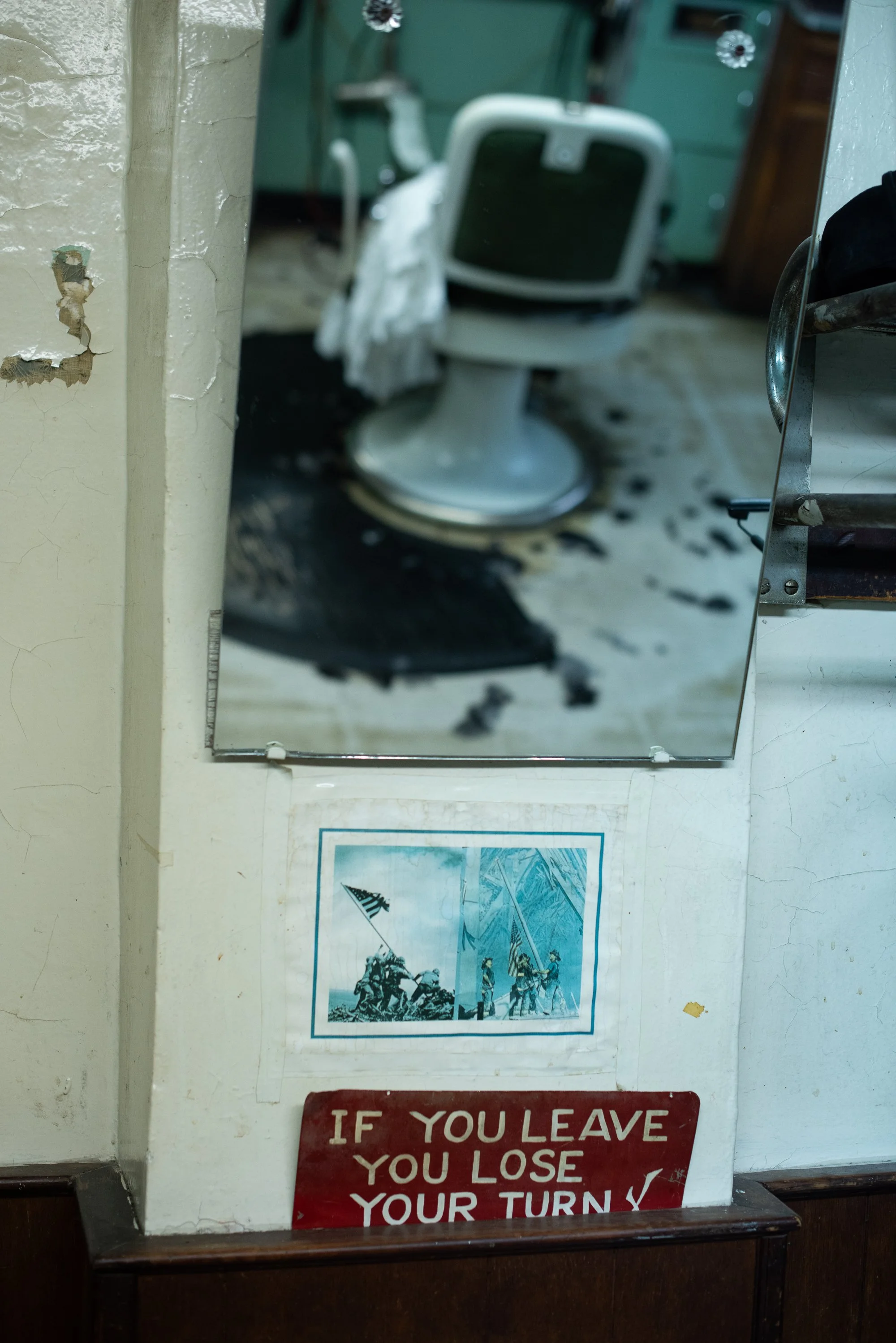 A worn barber chair reflected in a mirror inside Tony’s Barbershop in Brooklyn, New York.