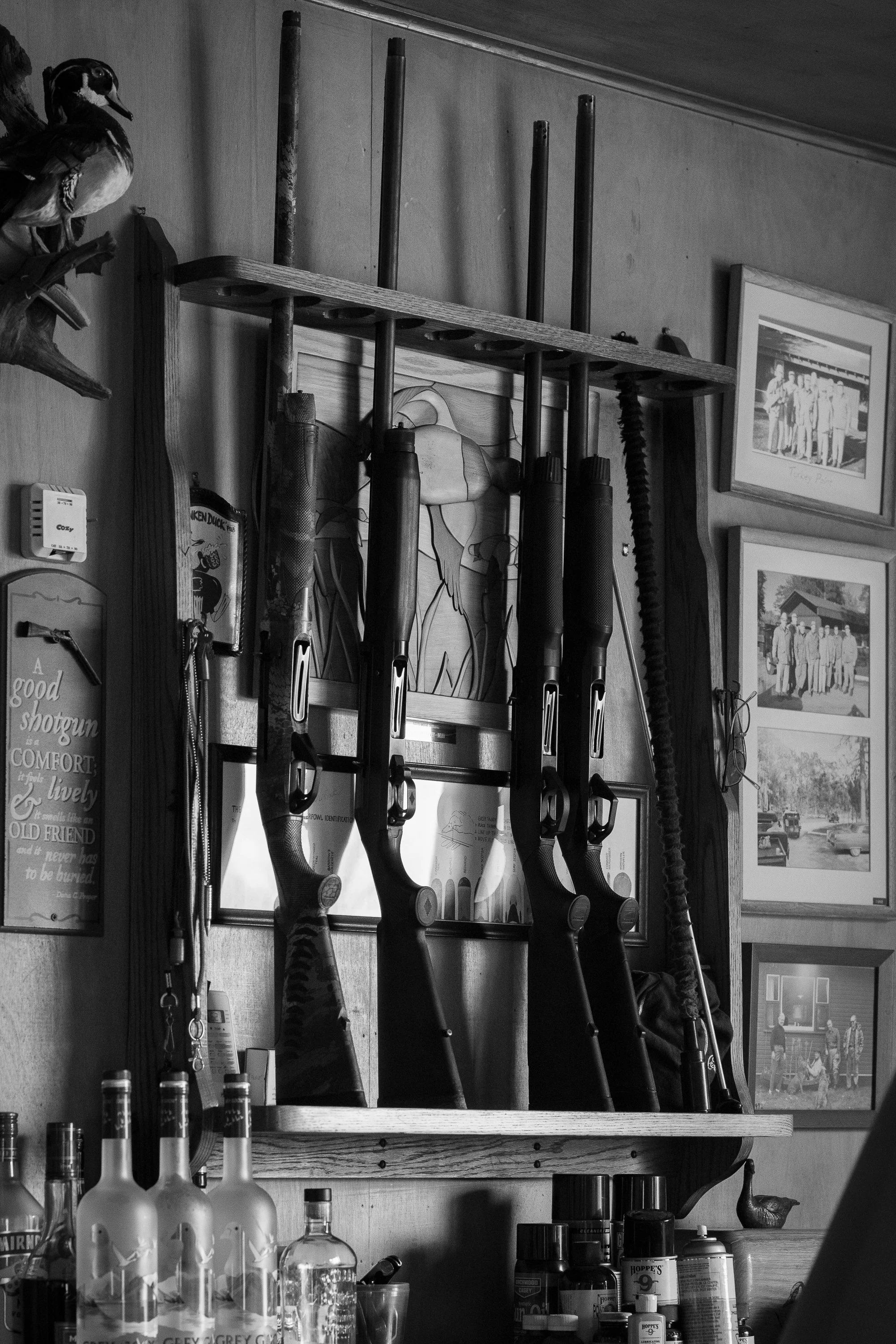Shotguns, framed photographs, and hunting gear line the walls inside a duck hunting lodge in Ontario