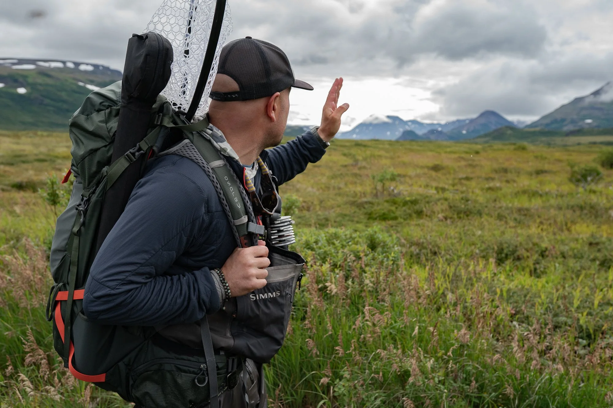 Fly fisherman carrying a backpack and fishing gear through Alaskan tundra