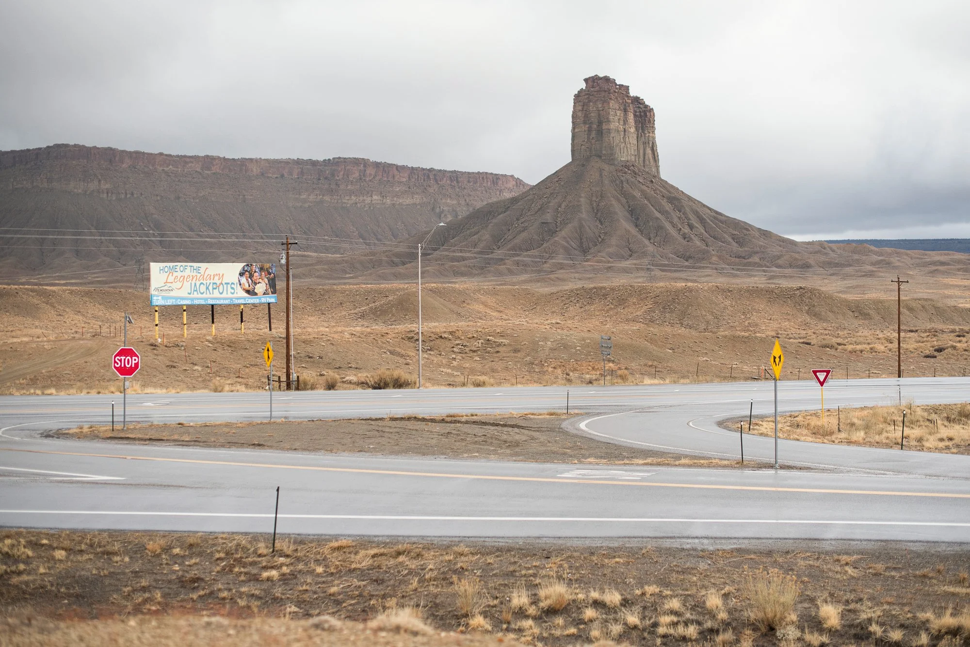 Remote desert intersection with road signs and butte formation in background