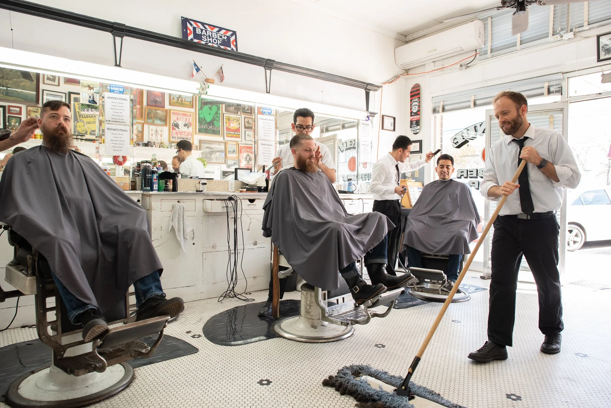 A barber sweeps the floor between chairs inside Avenue Barbershop