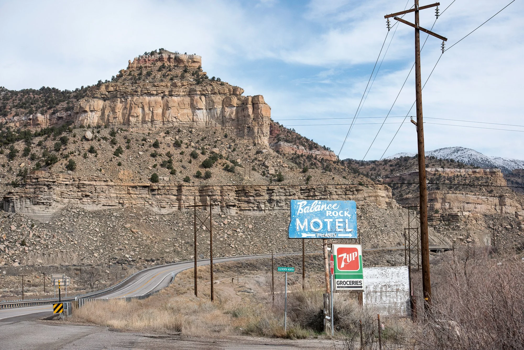 Vintage motel sign and roadside signage with canyon cliffs and winding road