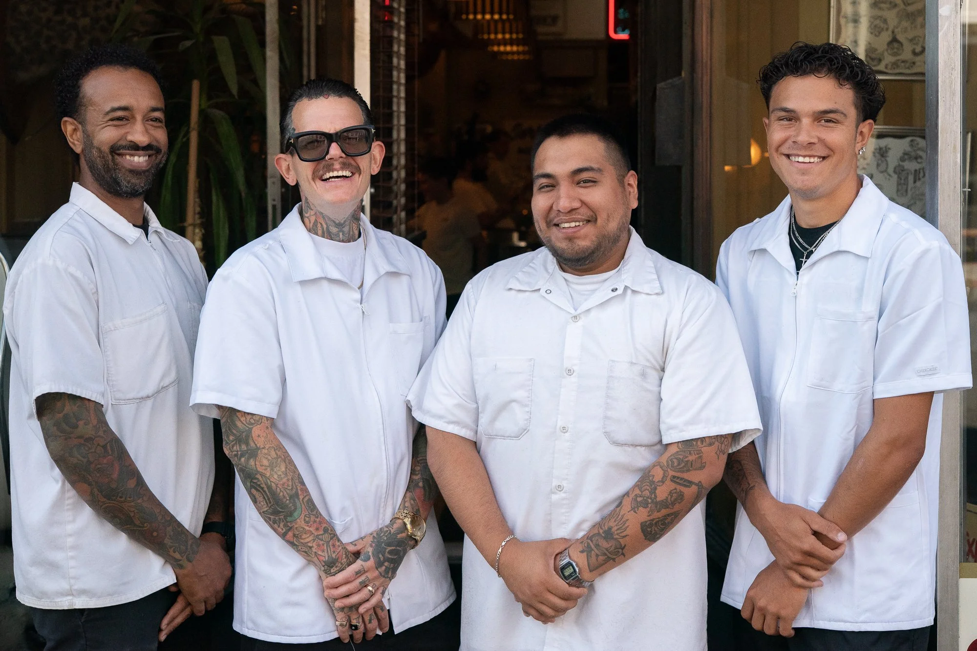 Four barbers standing together in the doorway of Pugsly's barbershop.