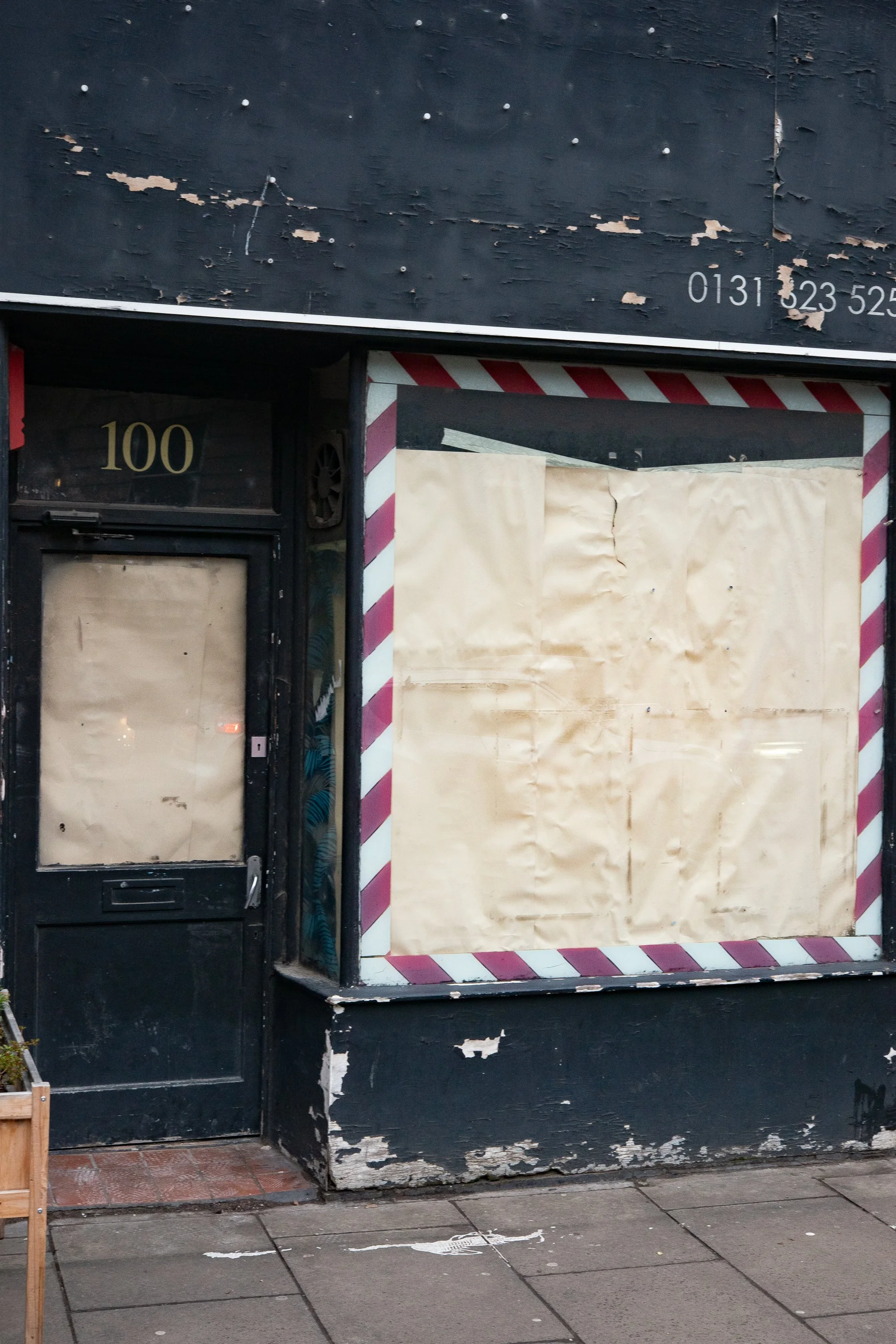 boarded-up barbershop storefront with striped trim and peeling paint in scotland
