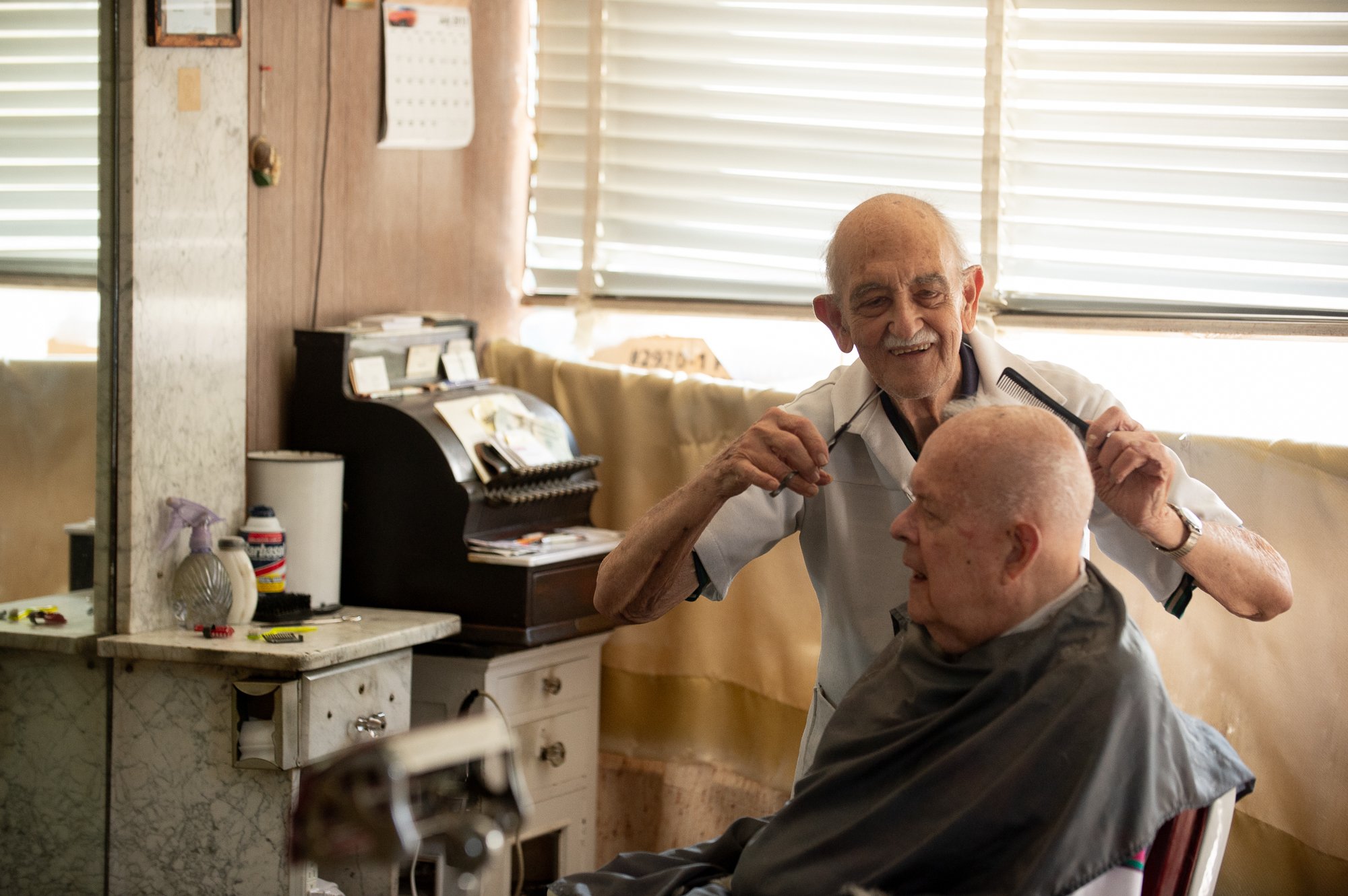 elderly barber Tony cutting a customer's hair inside his Greenwich Connecticut barbershop