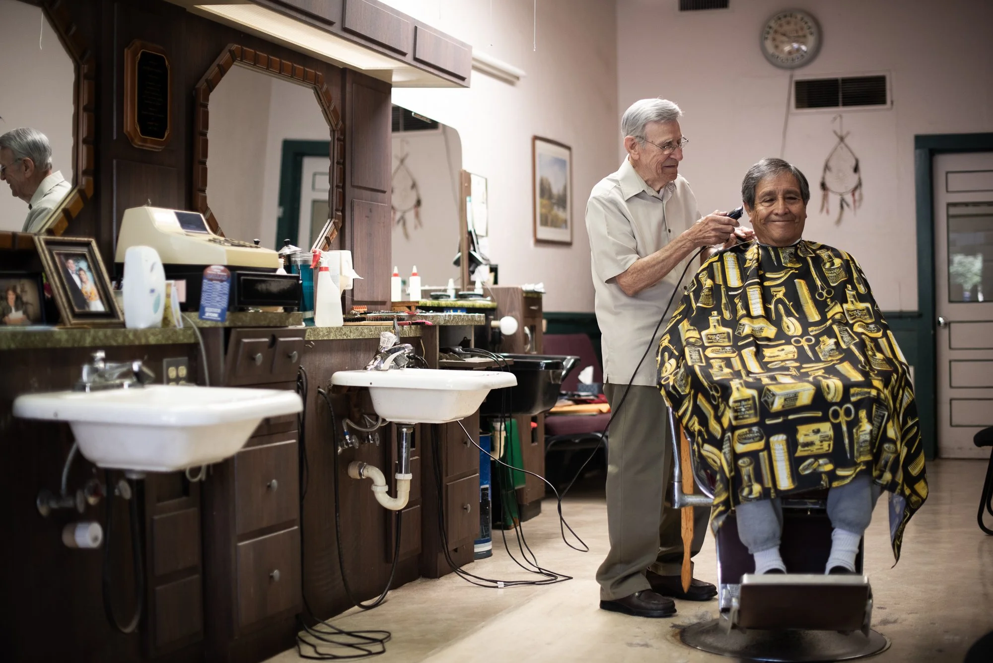 Barber giving a haircut to a customer inside Raymond’s Barber Shop in Lockhart, Texas.