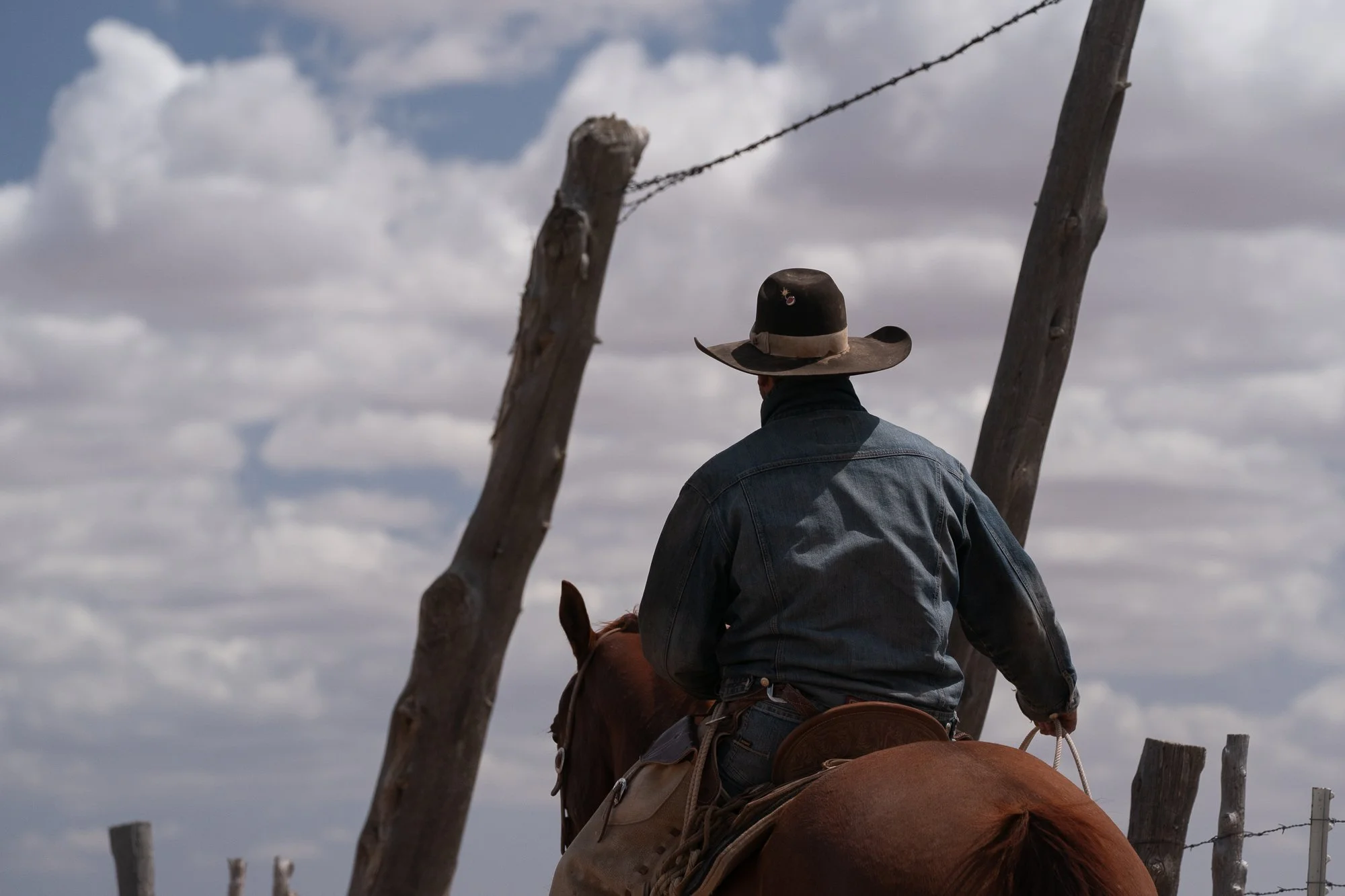 Cowboy on horseback riding near a fence on the Diamond A Ranch in Arizona