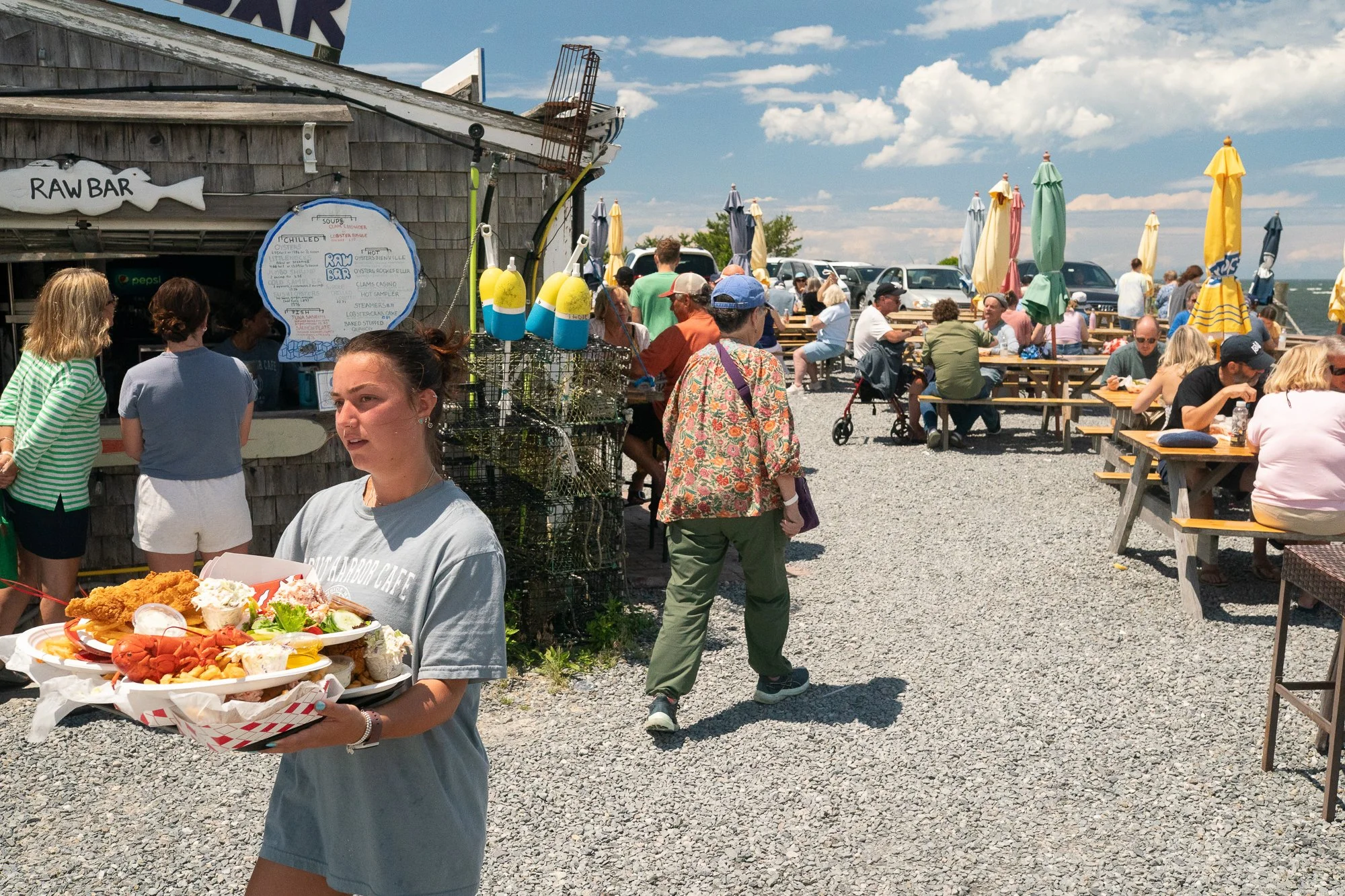 People gathered at Sesuit Harbor Cafe raw bar on Cape Cod with seafood plates and outdoor seating