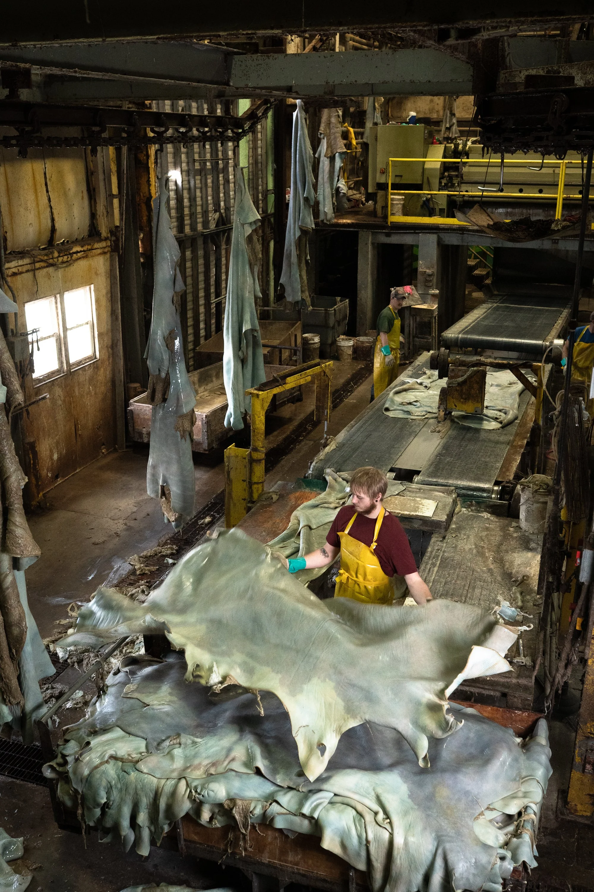Workers handle leather hides beside machinery inside the Wickett & Craig tannery in Pennsylvania