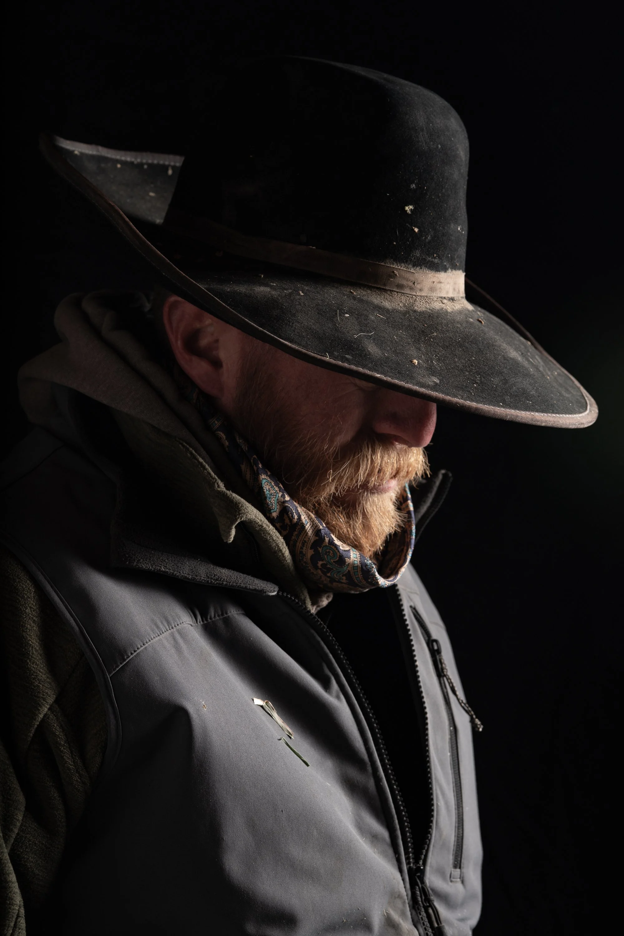 Moody portrait of cowboy in hat with dramatic light and shadow