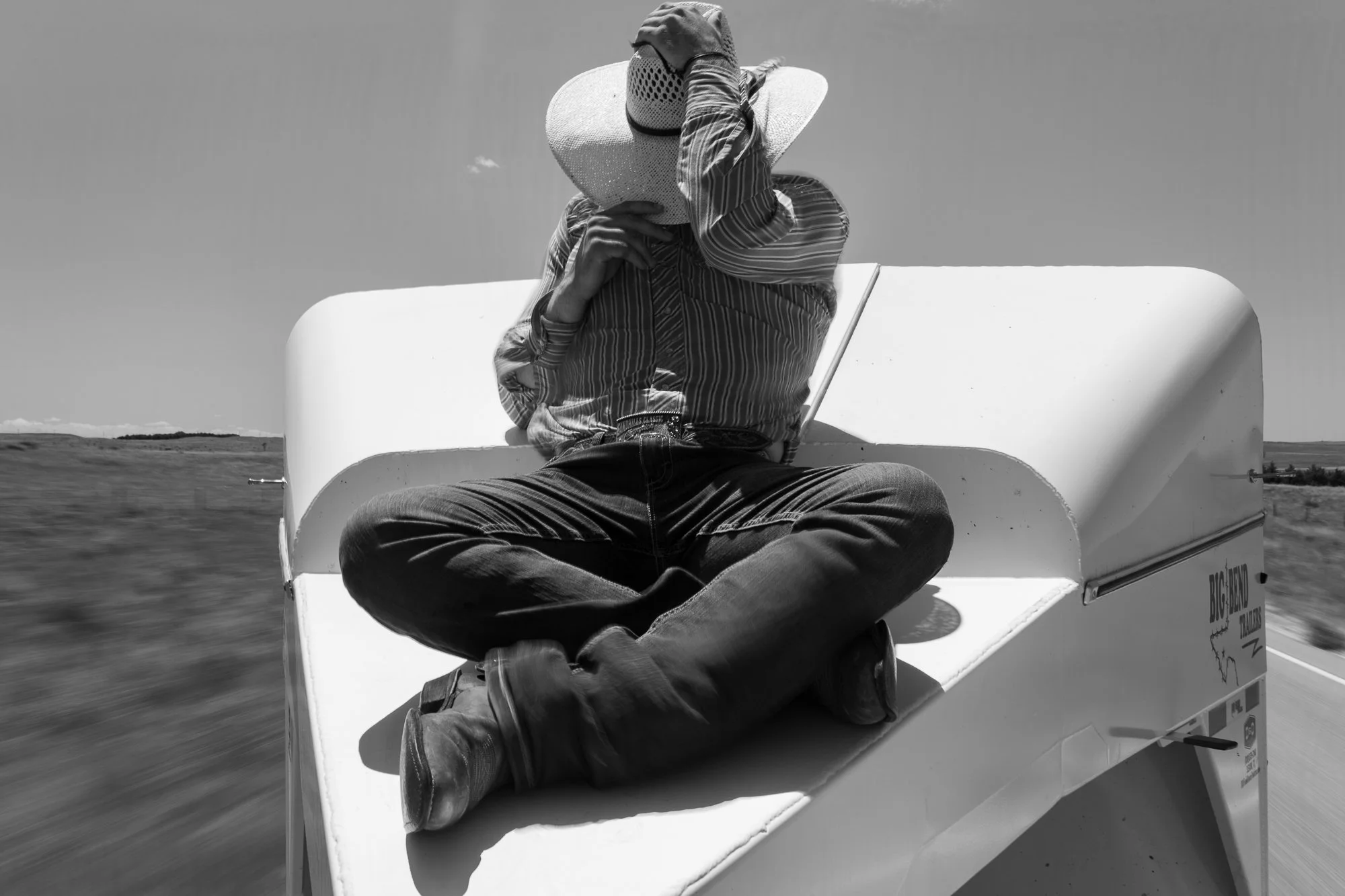 Cowboy riding on top of a moving horse trailer in Nebraska