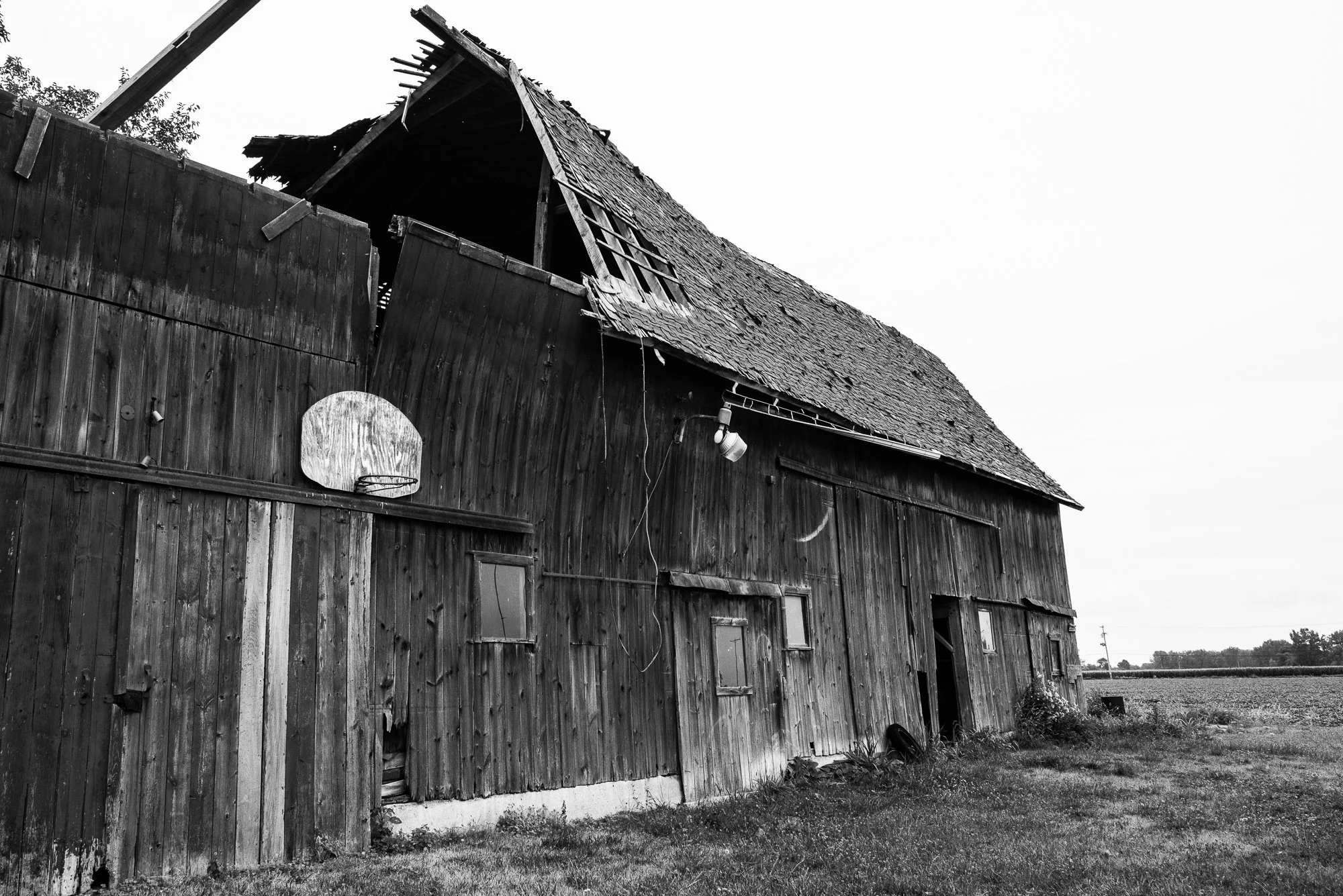 Basketball hoop mounted on a weathered barn with a damaged roof
