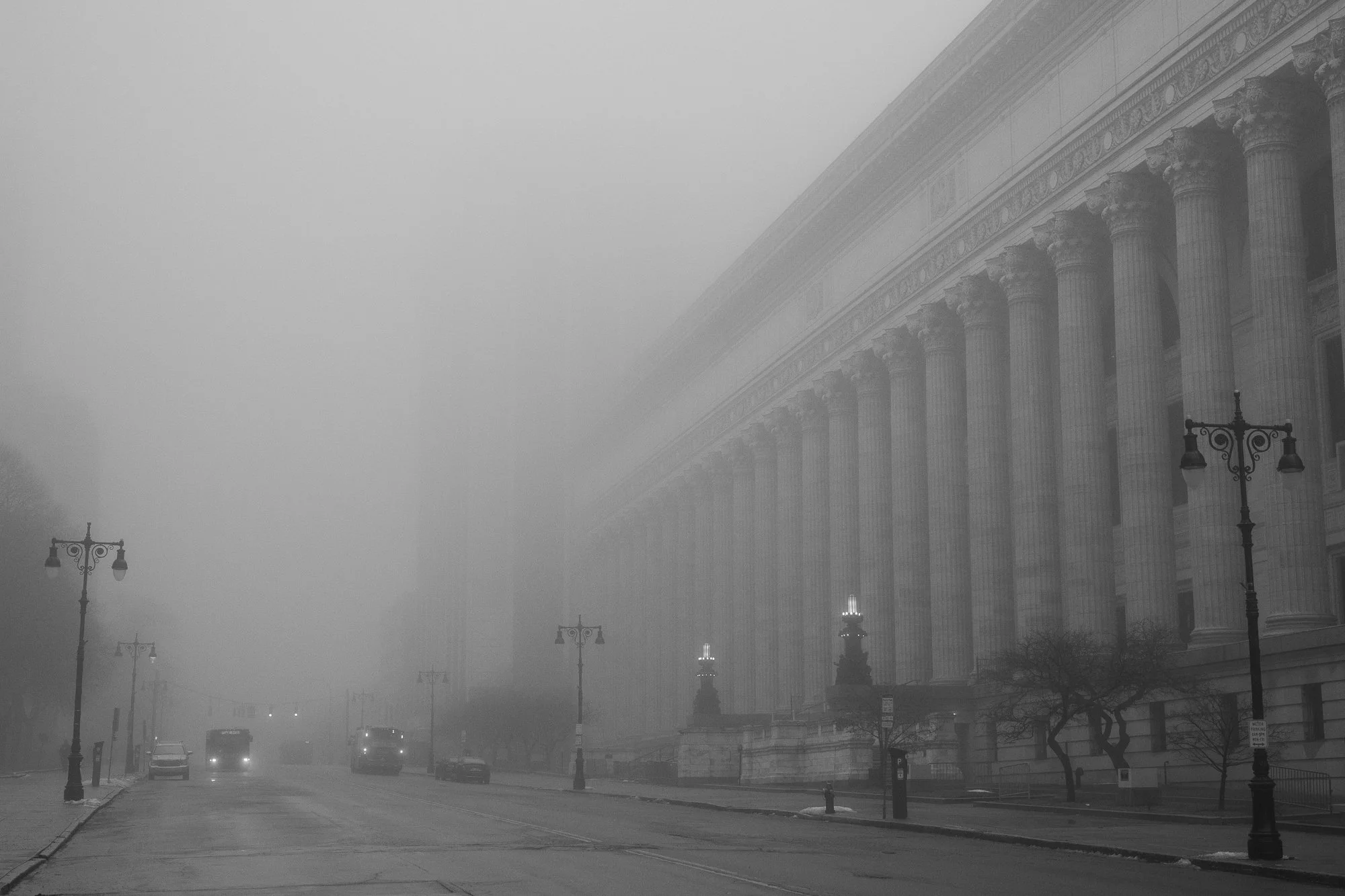 Black and white photograph of a columned government building along an empty street in Albany
