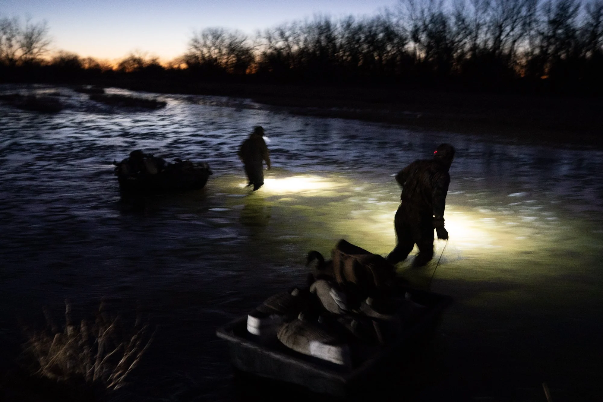 Duck hunters wade through marsh water at first light in Nebraska