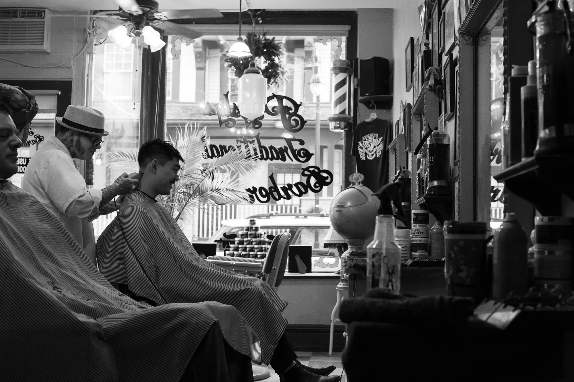 Barber cutting a client's hair inside Pugsly's SideShow Barbershop in Kingston, New York.