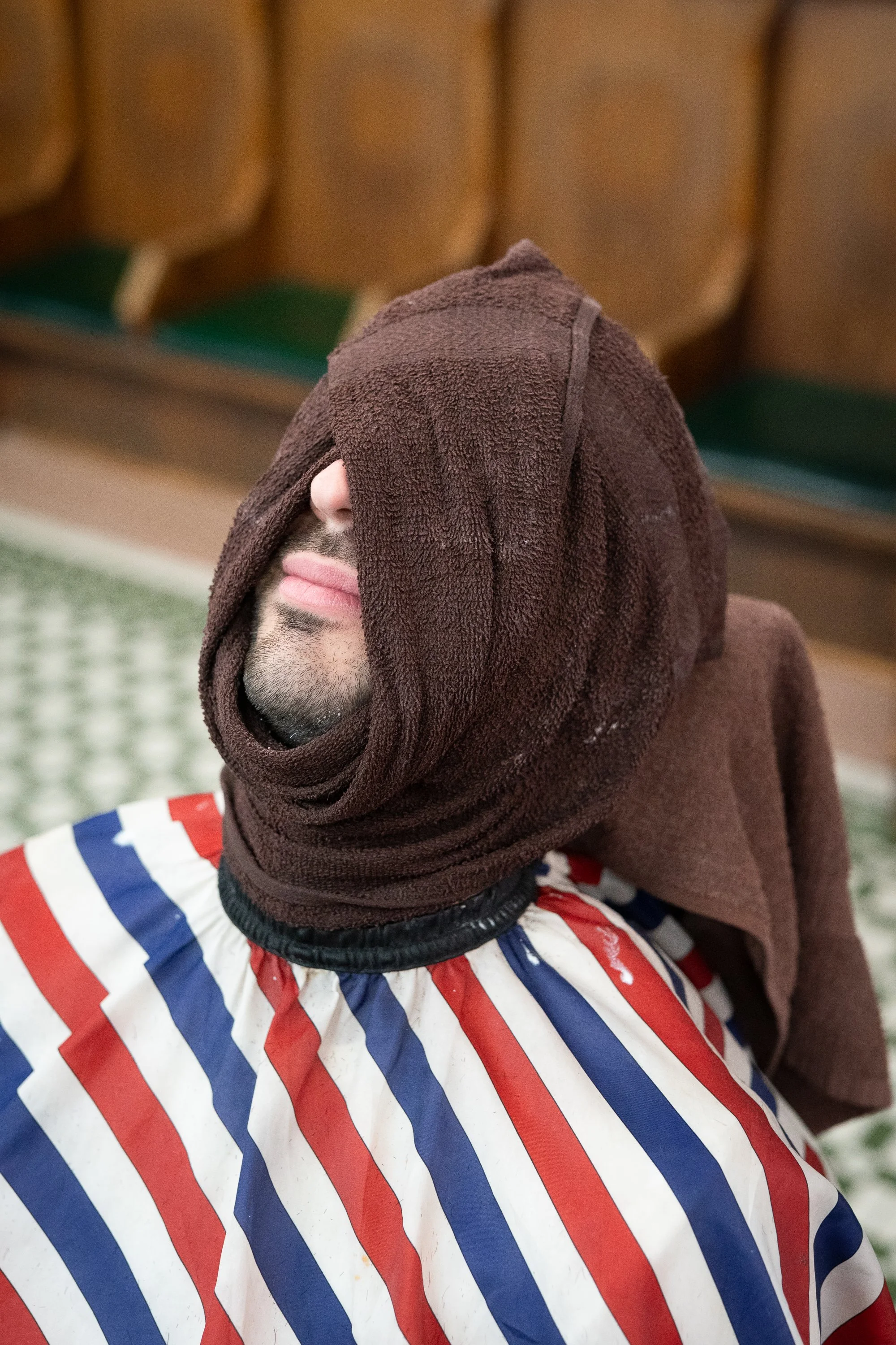 Client reclined with a hot towel over his face at Patsy’s Barbershop in Albany New York