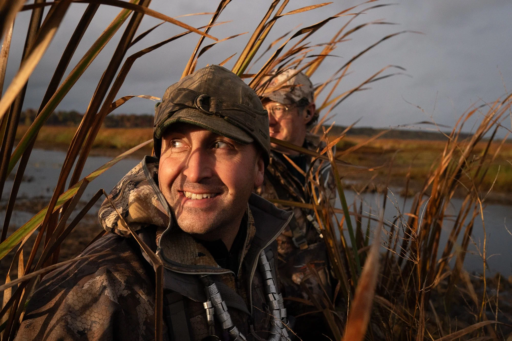 Two duck hunters sit concealed in marsh reeds during duck hunting season in Ontario