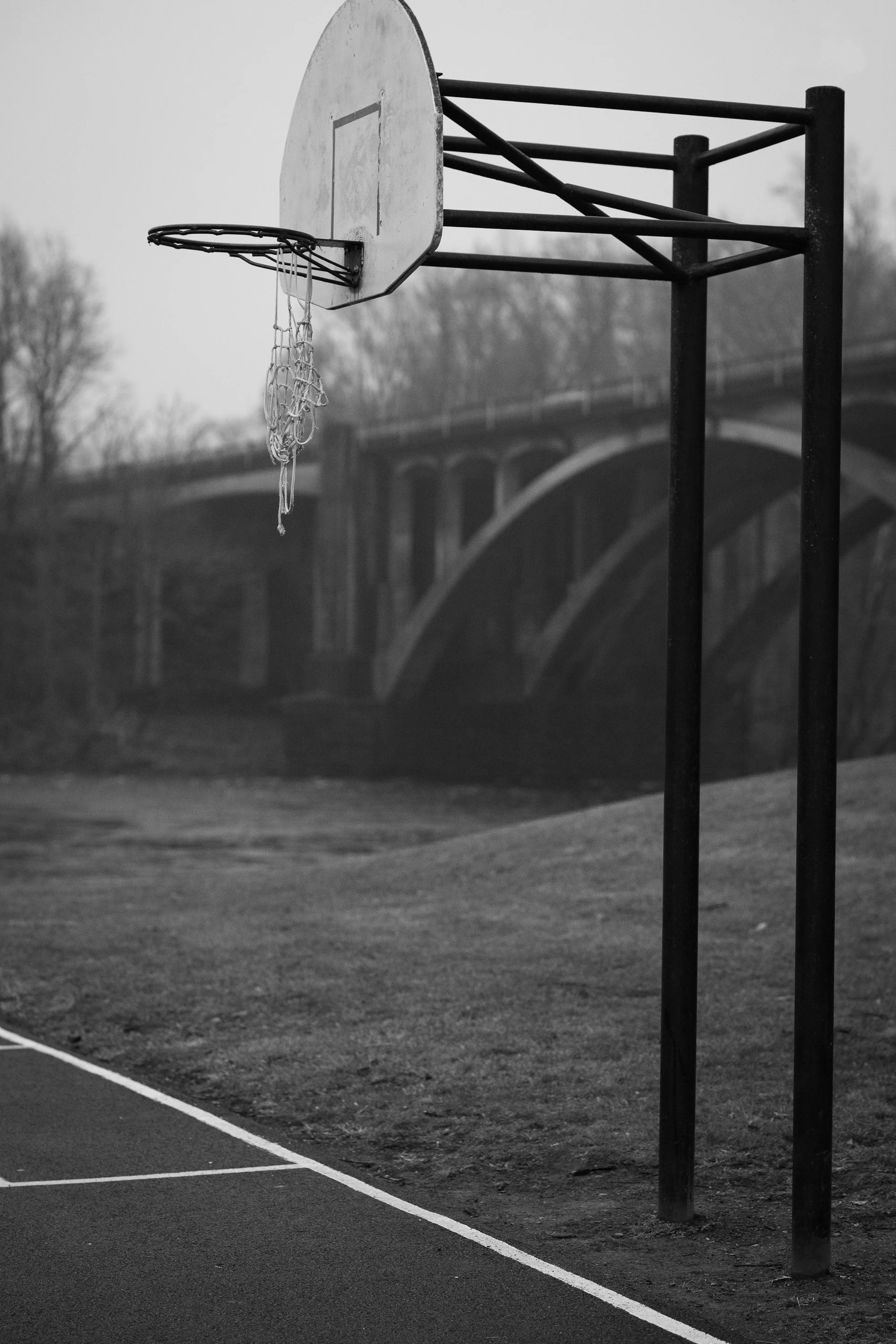 Basketball hoop near a bridge on an outdoor basketball court