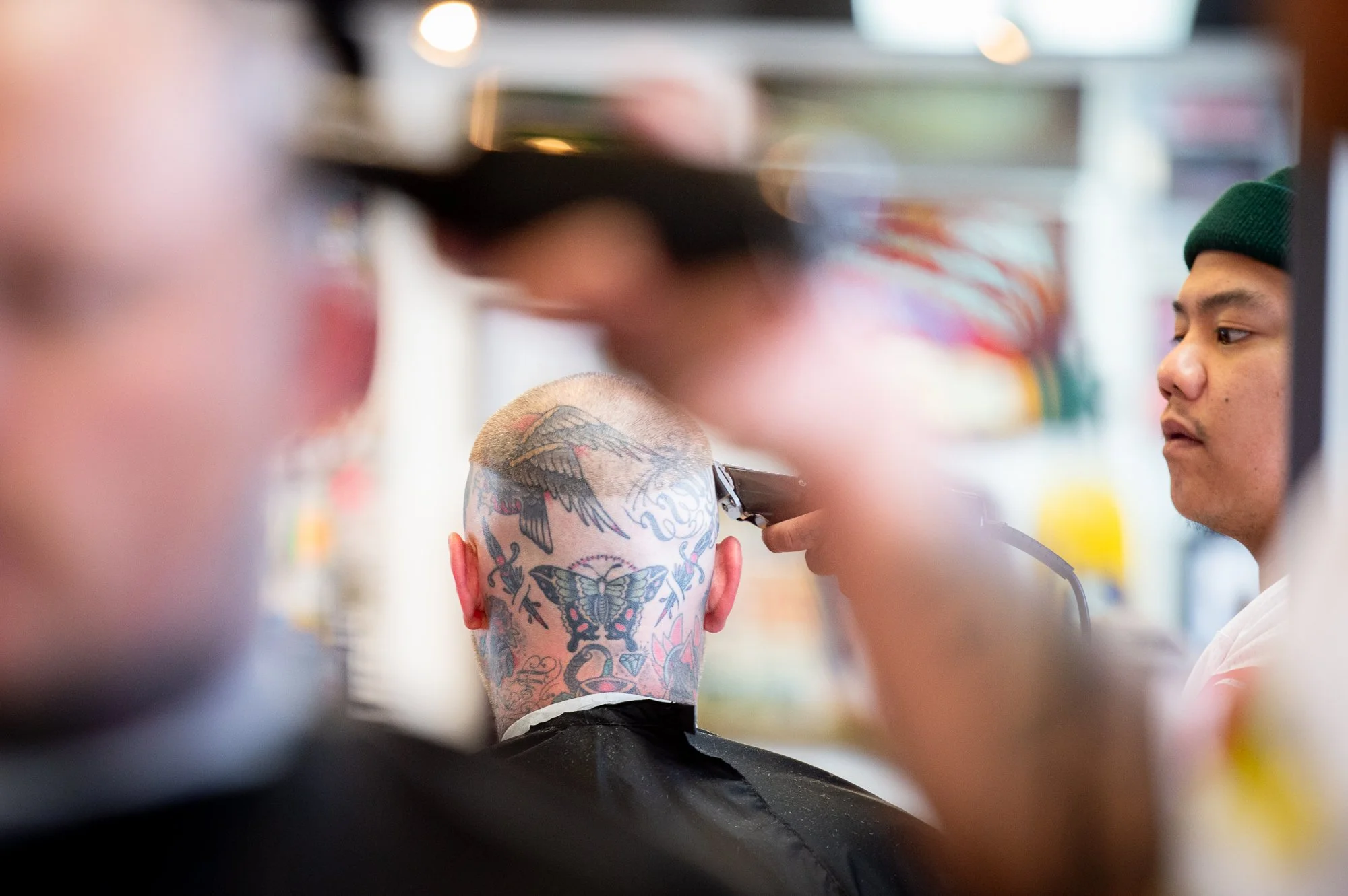 client with tattooed head getting haircut inside Shane's Barbershop San Mateo