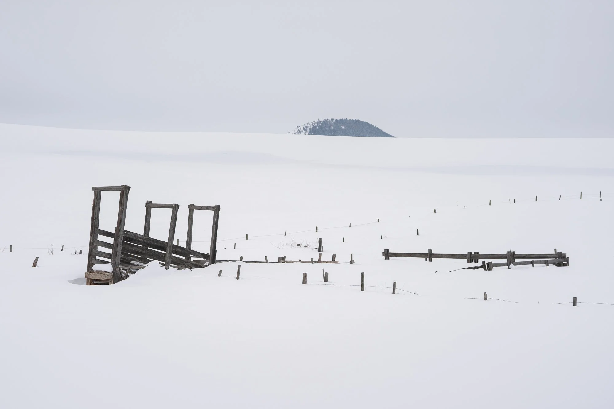 Old corral partially buried in snow on an open ranch landscape in the American West